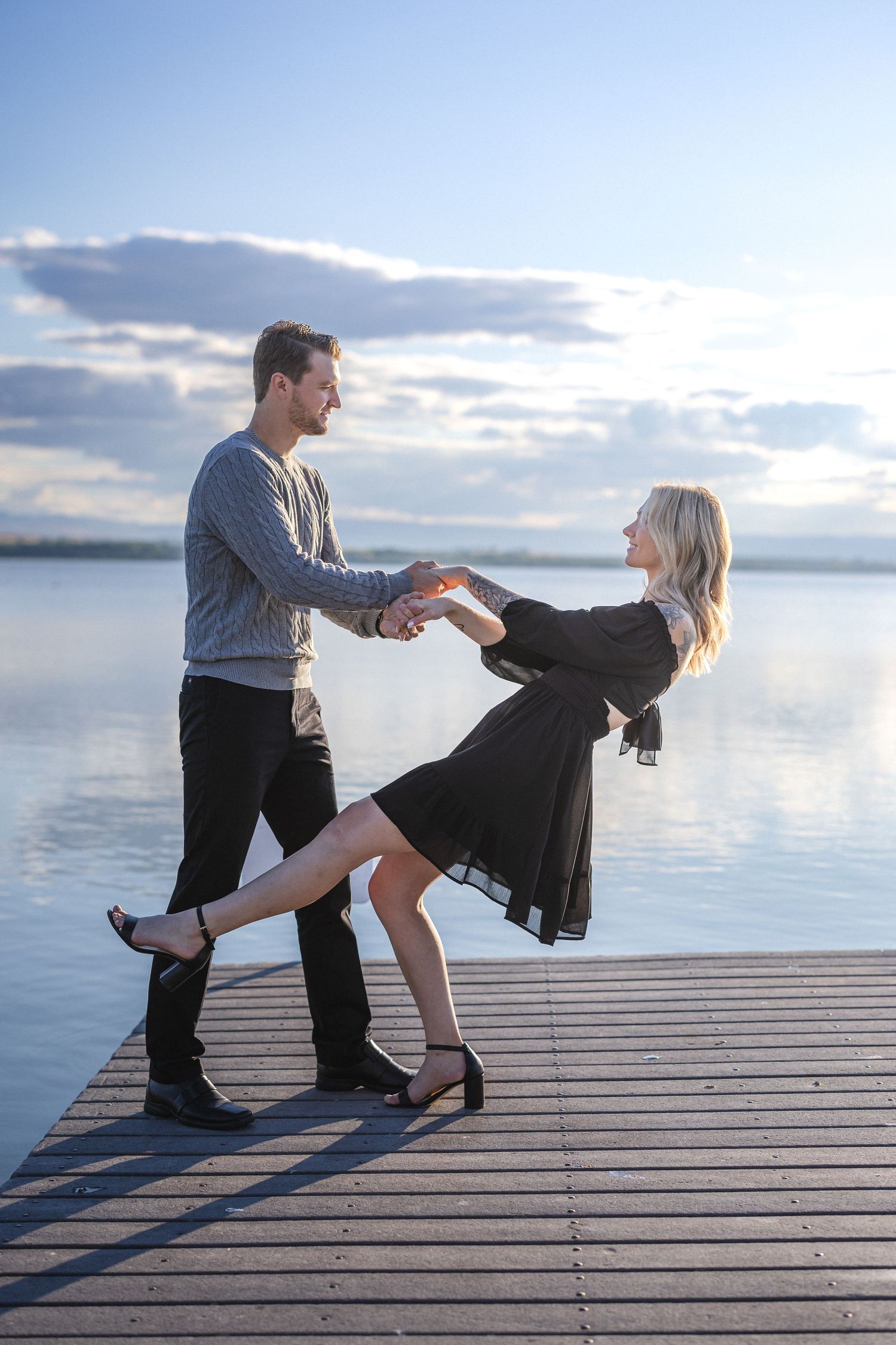 Couple dancing together on wooden dock with tranquil lake views.