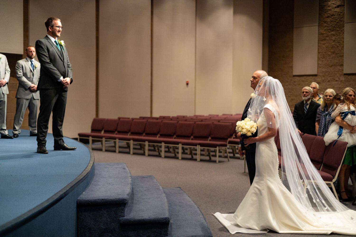 Wedding ceremony in a modern church venue with elegant white seating arrangements.