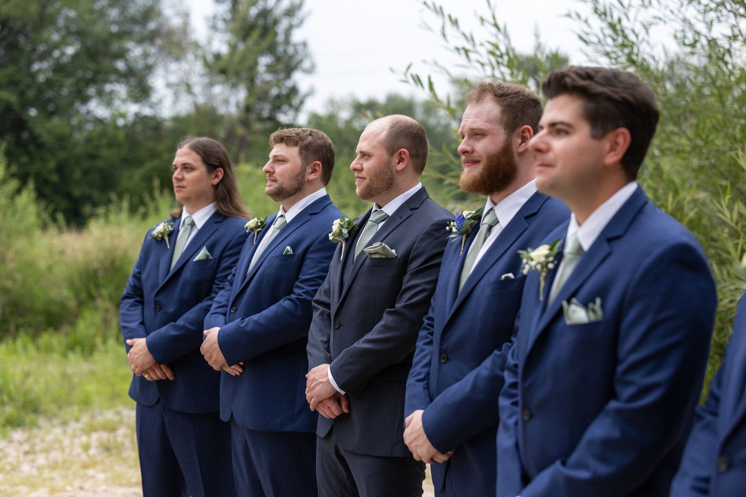 Groomsmen lined up wearing matching navy suits with boutonnieres.