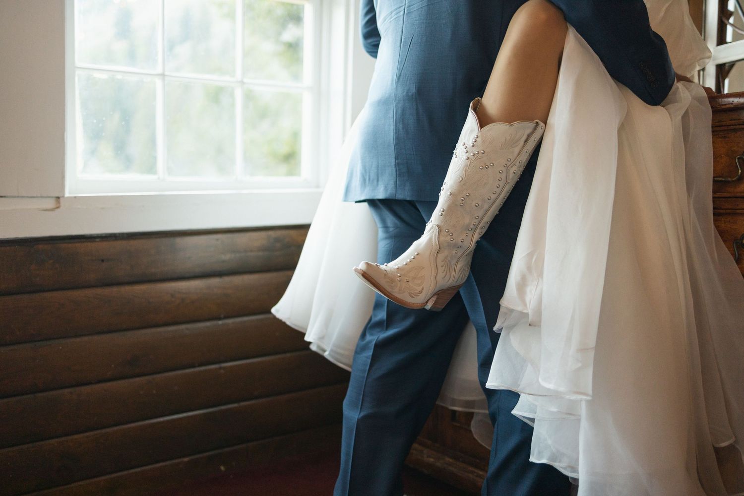 Wedding couple embracing in intimate poses by window with natural light.