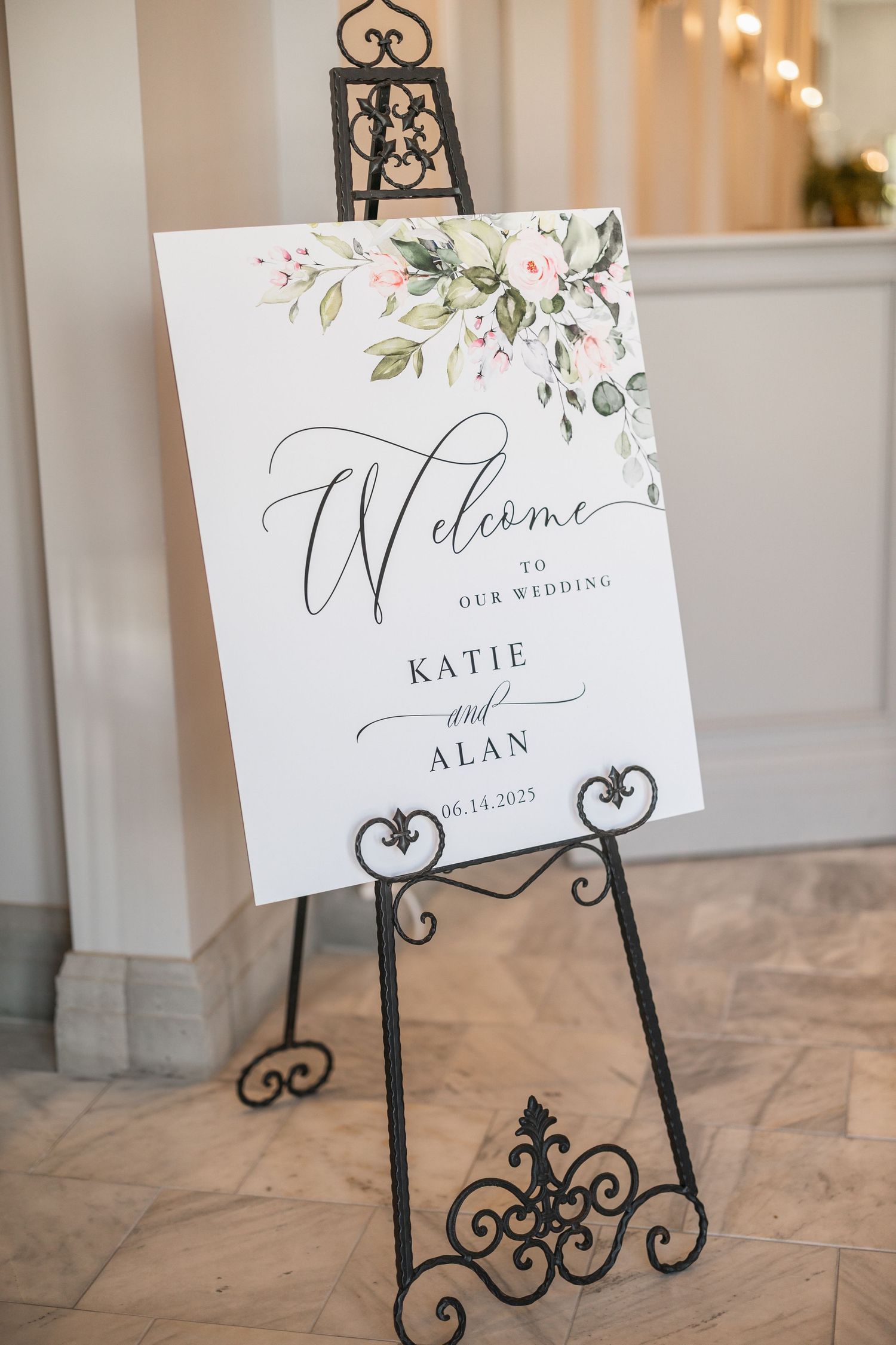 Elegant wedding welcome signs displayed on decorative black metal easels with floral accents.