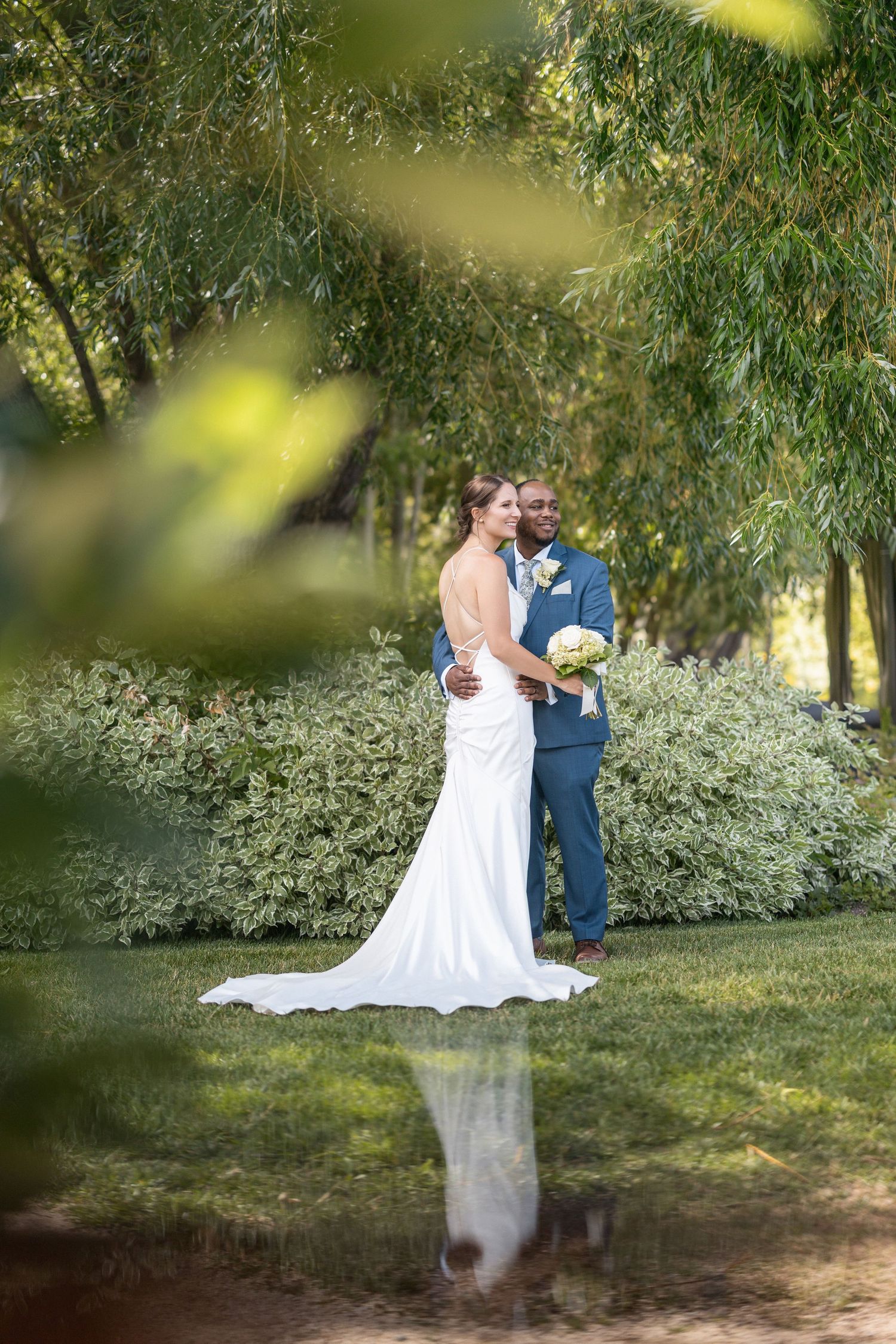 An intimate wedding moment captured in a sunlit garden with natural greenery.