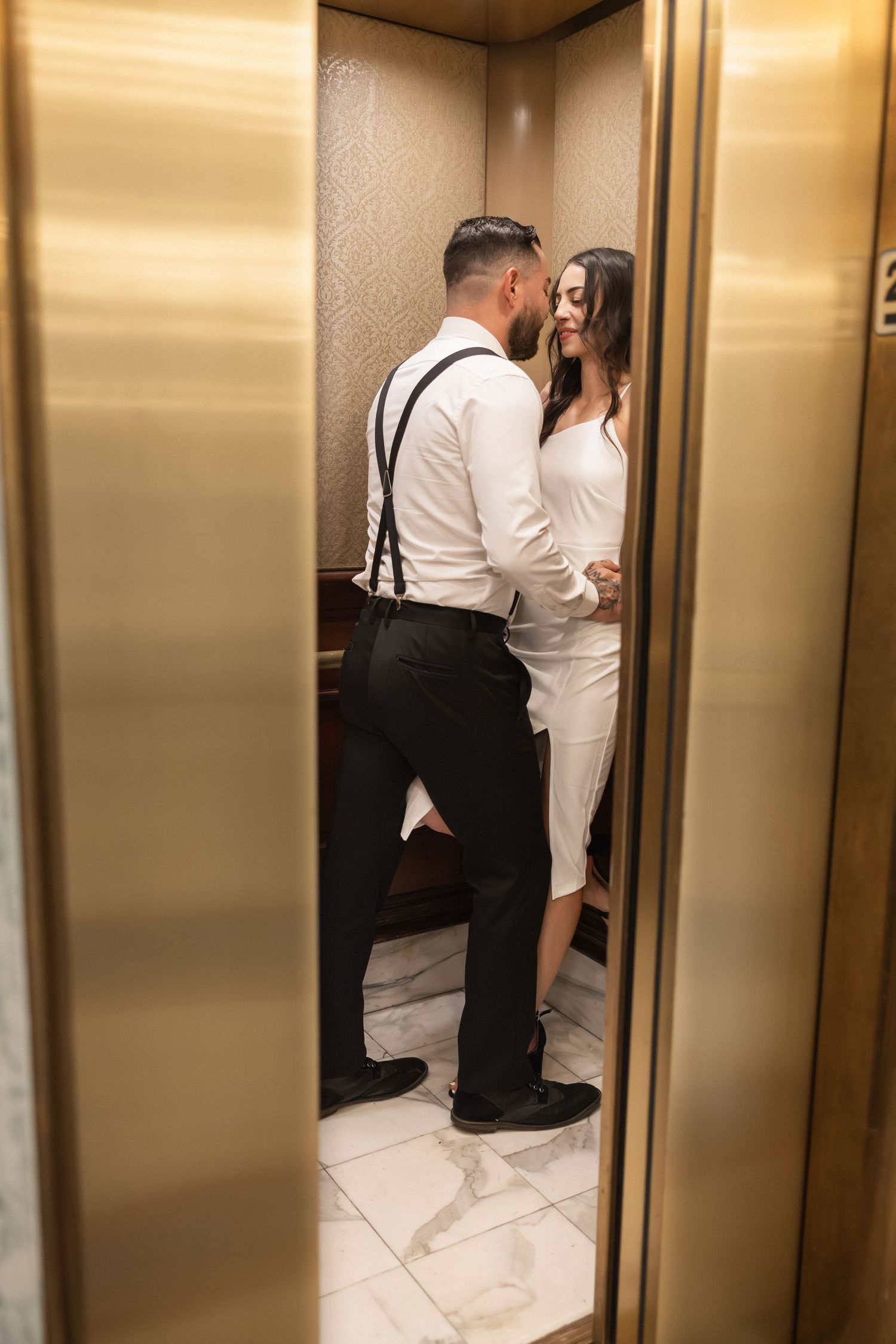 A romantic moment captured between a couple in formal attire sharing an intimate embrace in an elevator.