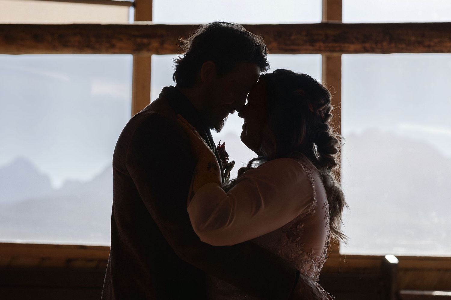 Silhouetted figures against bright windows in rustic wooden interior.