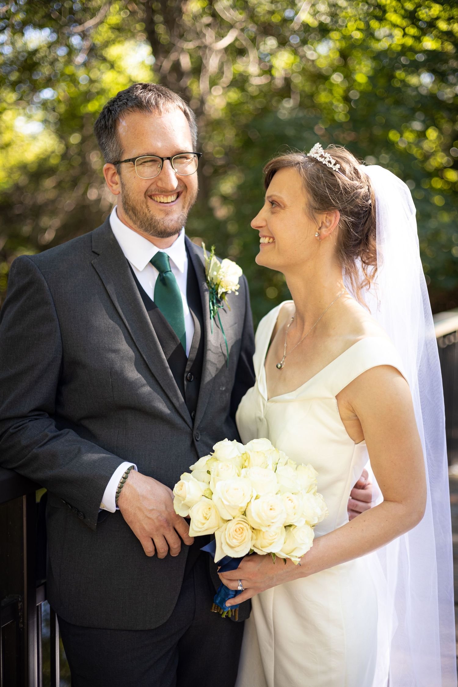 Couple shares joyful moments while holding white roses on their wedding day.