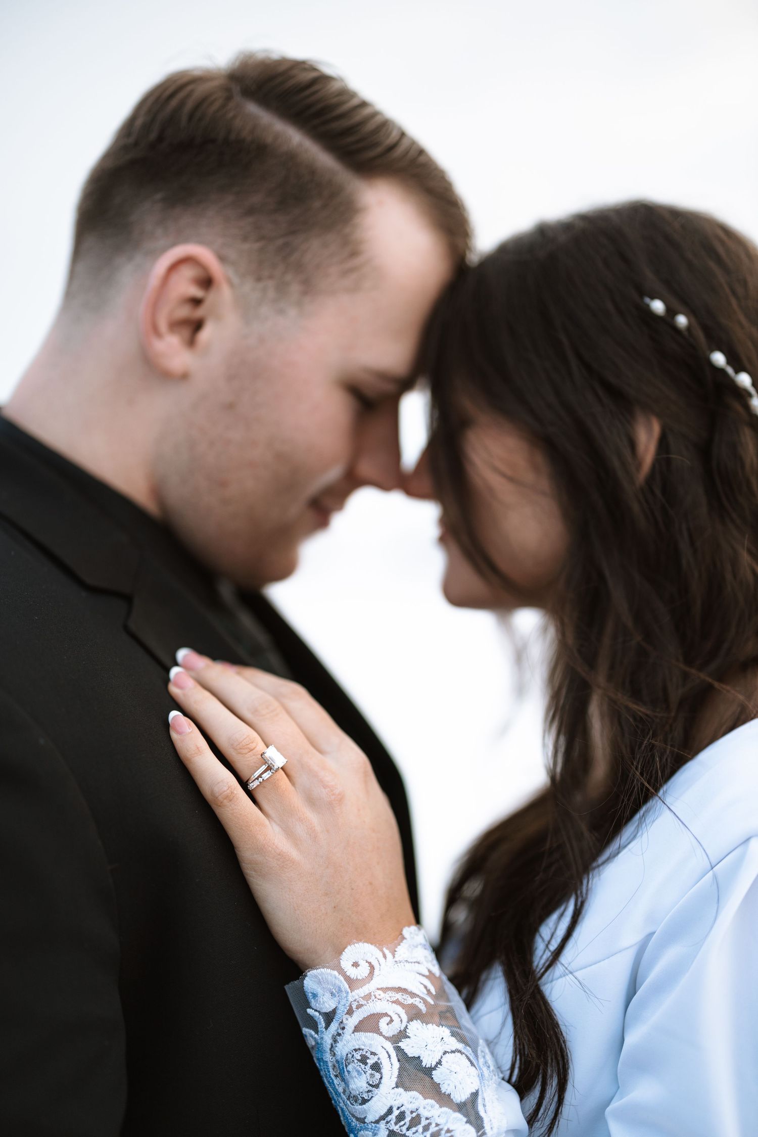 Close-up portrait showing wedding ring and intricate lace sleeve details.