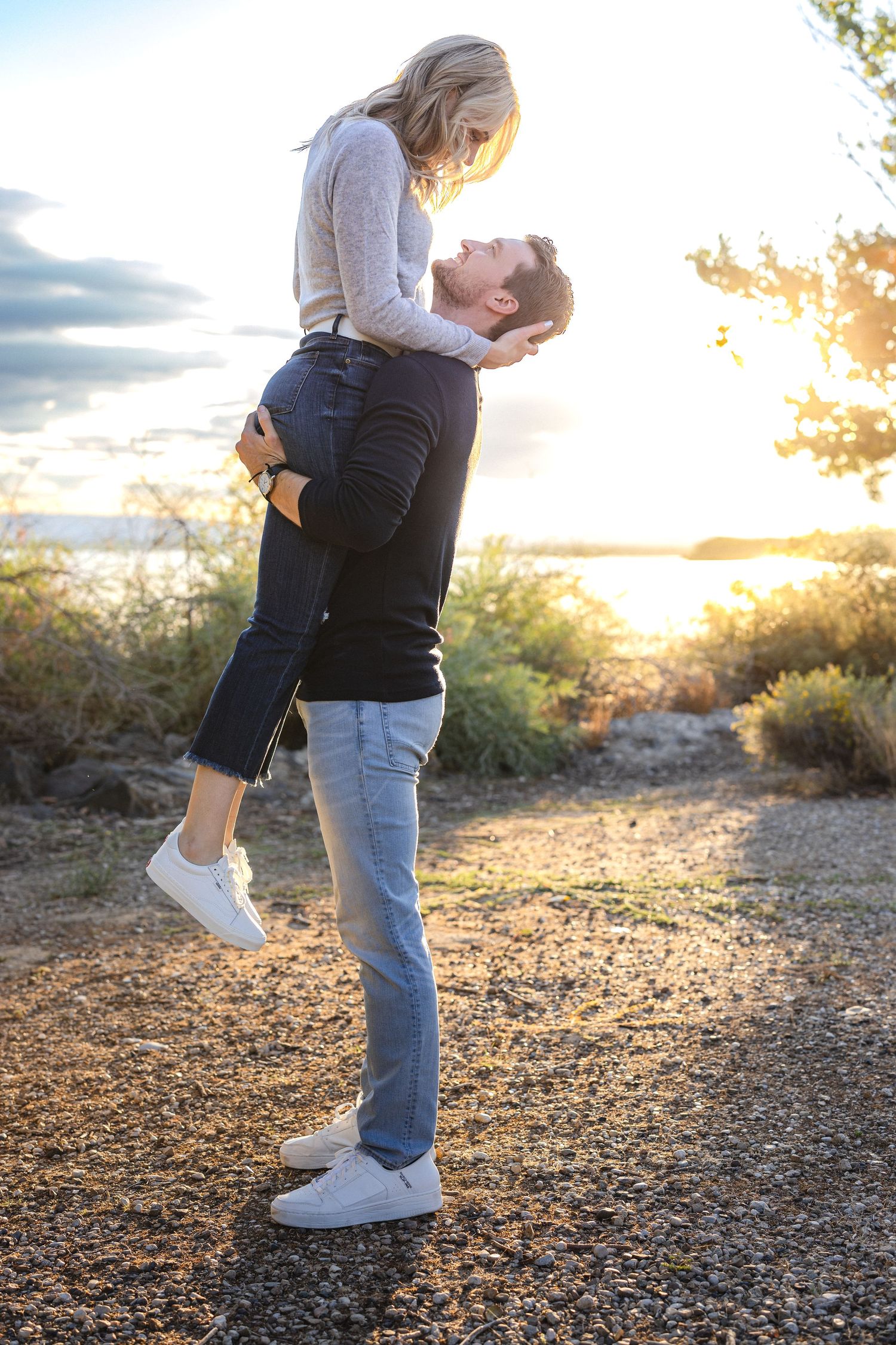Playful lift pose during golden hour with desert landscape in background.
