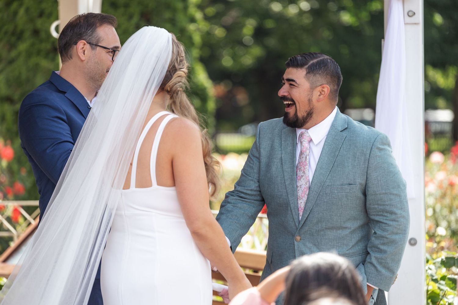 Intimate moment during outdoor wedding ceremony beneath white gazebo.