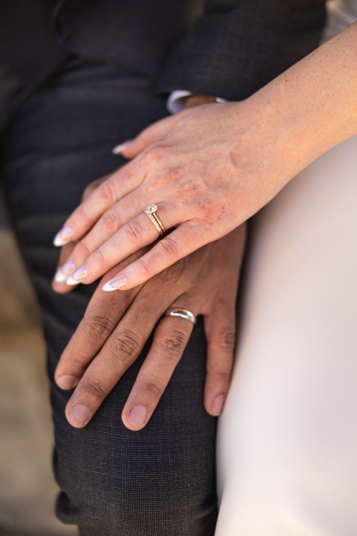Close up of newlywed couple's hands with wedding rings resting together.