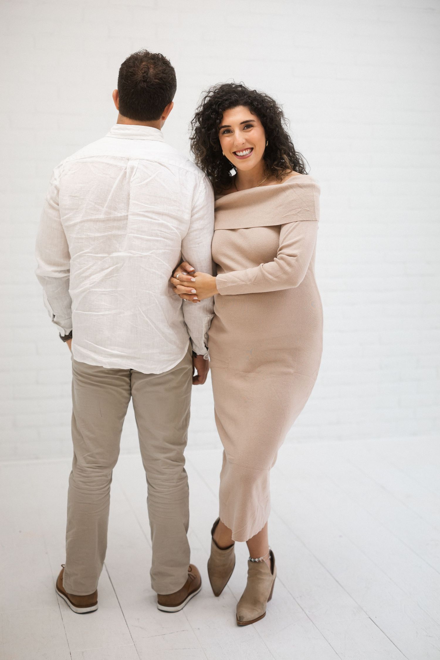 A series of four progressive shots showing a couple in neutral tones walking together on a white background.