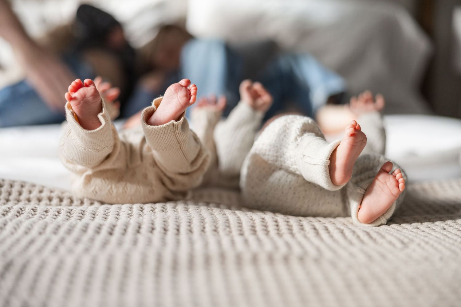 A close-up view of tiny baby feet resting on soft white bedding.
