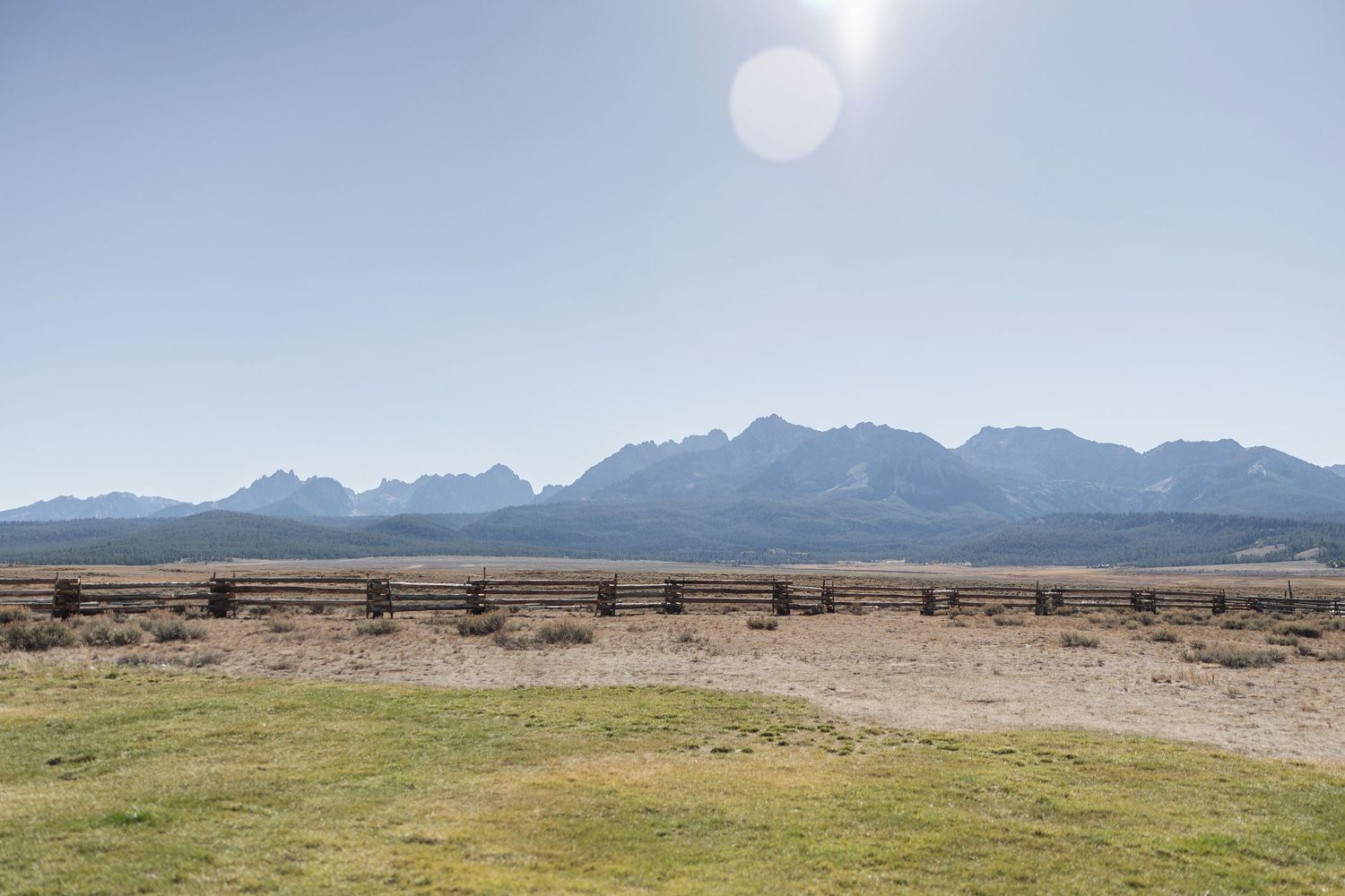 Rugged mountain range rises above desert plains under bright sunlight.