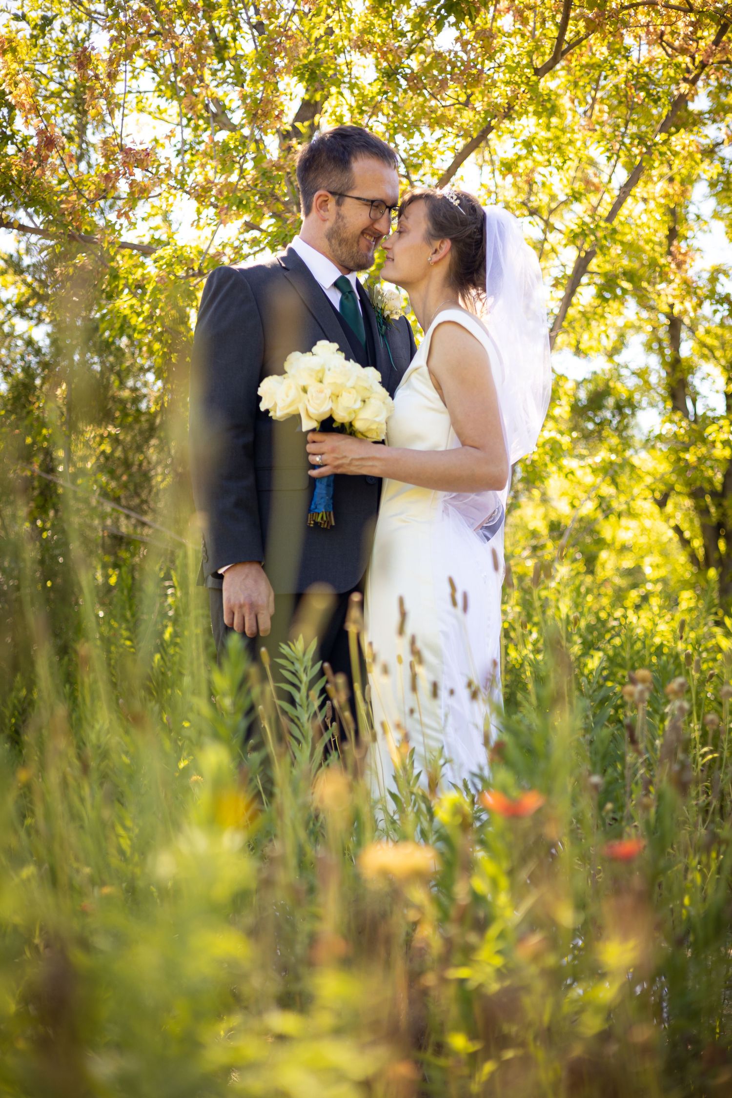 Romantic moment between newlyweds in a sunlit meadow with tall grass.