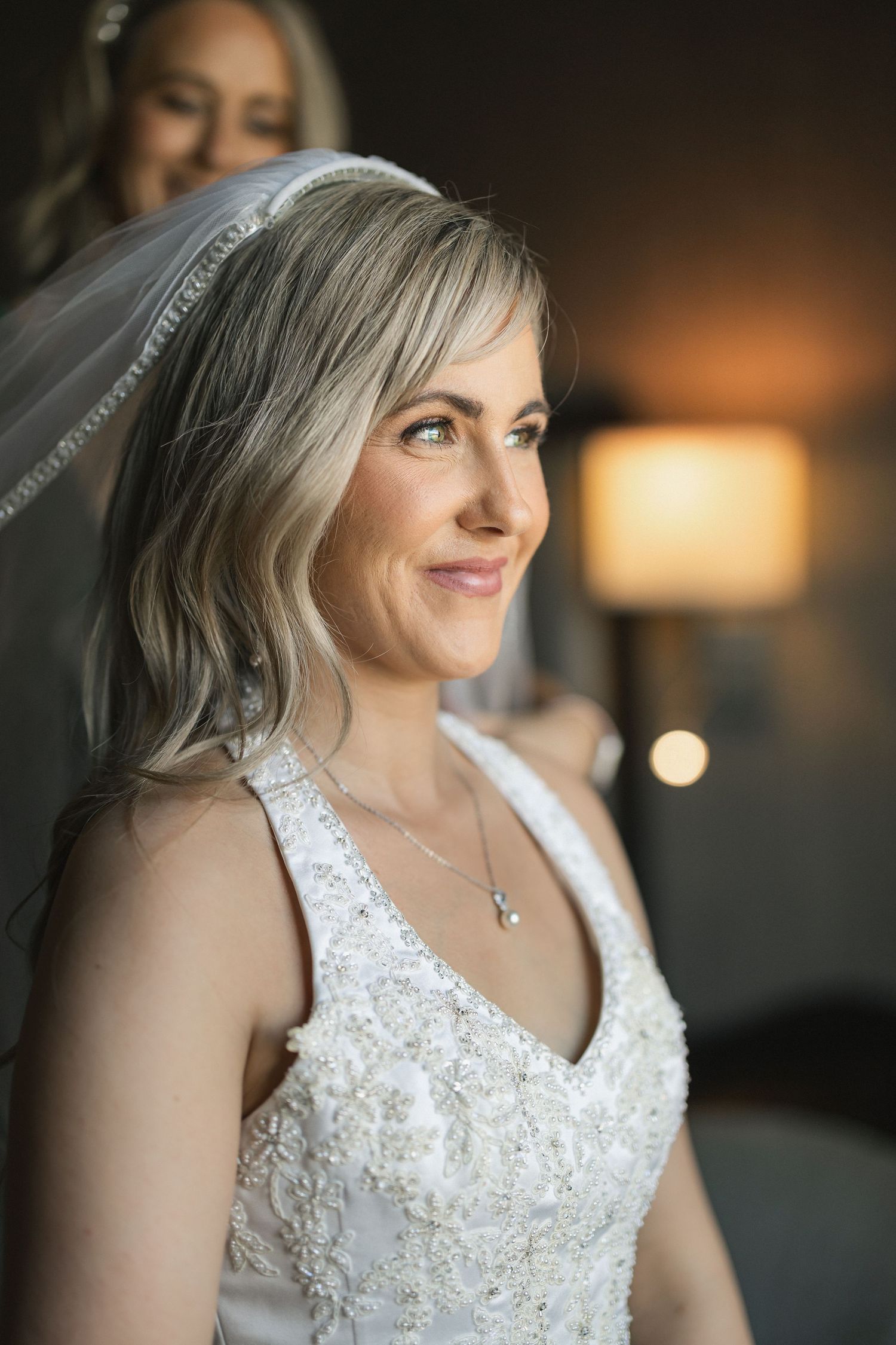 Radiant bride with blonde hair wearing lace wedding dress and veil.