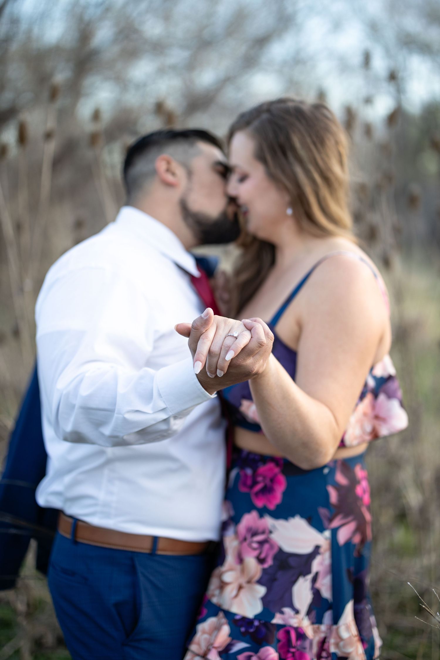 A couple shares an intimate moment while dancing in a field of dried plants.