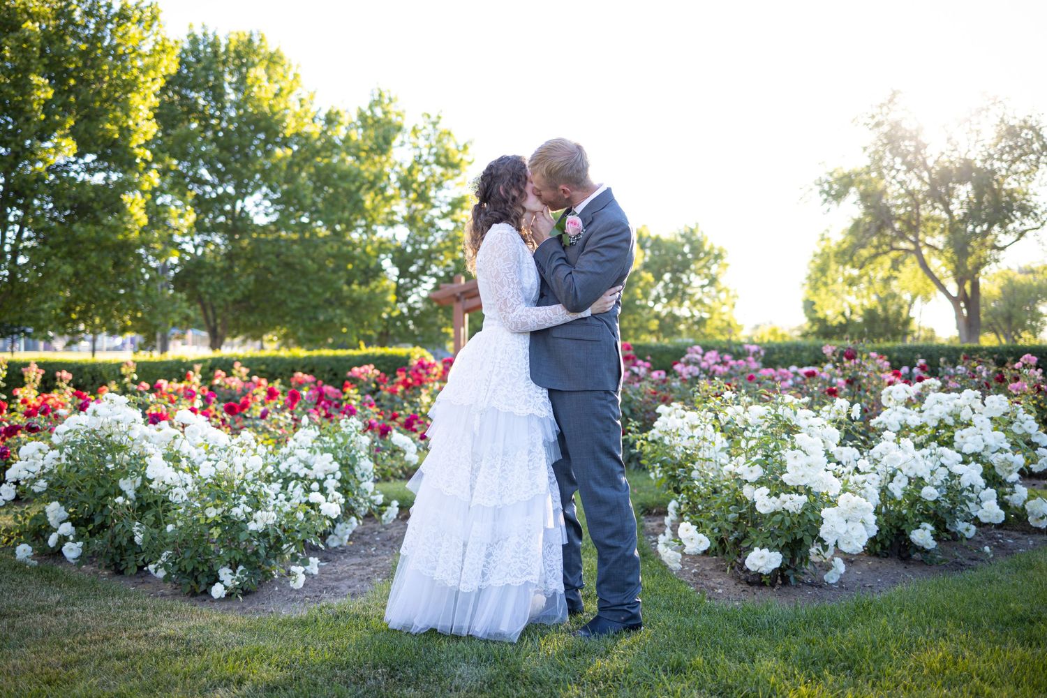 Romantic garden wedding photos with white roses and natural greenery in background.