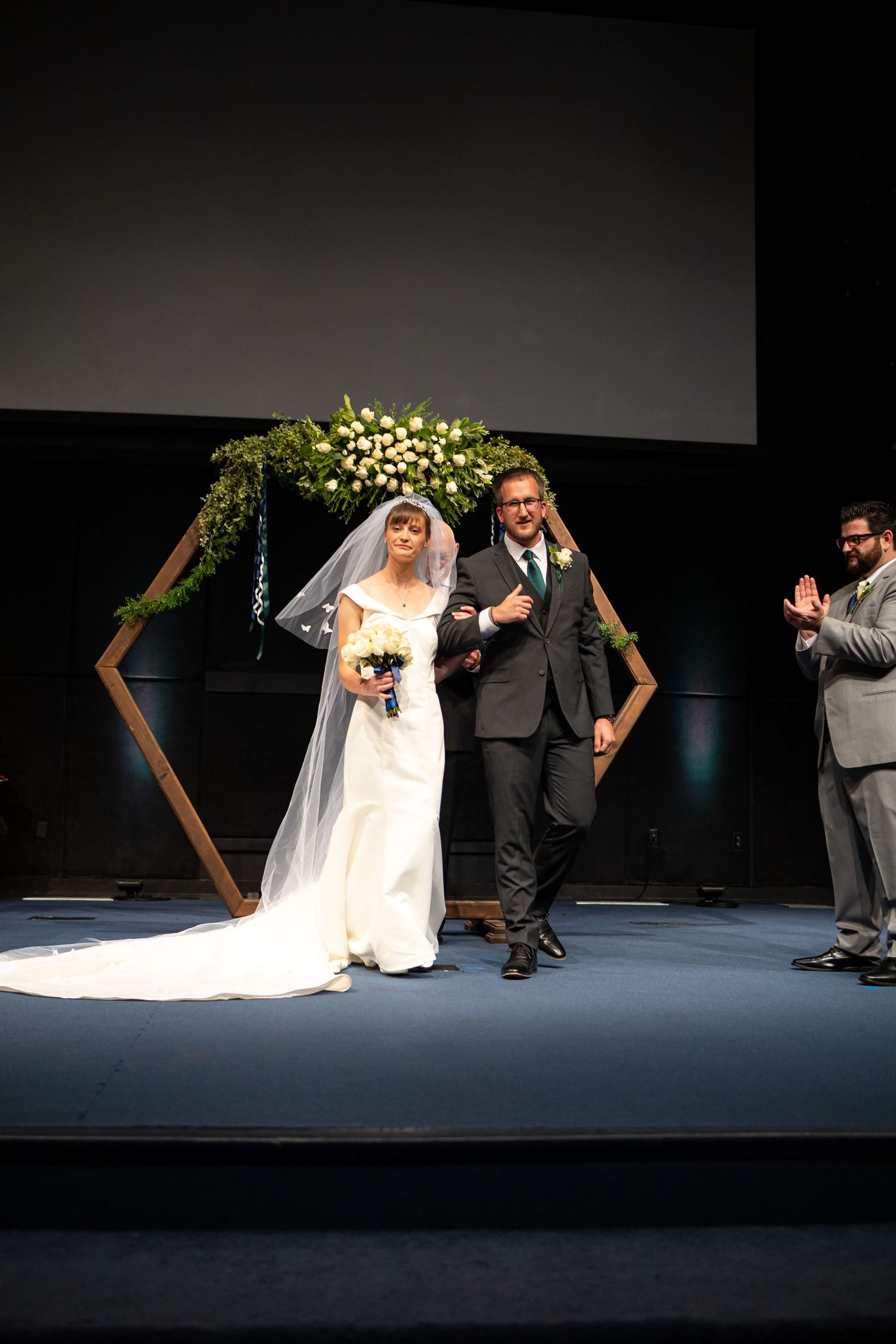 Newlyweds celebrate their first moments as a married couple under a modern geometric arch.