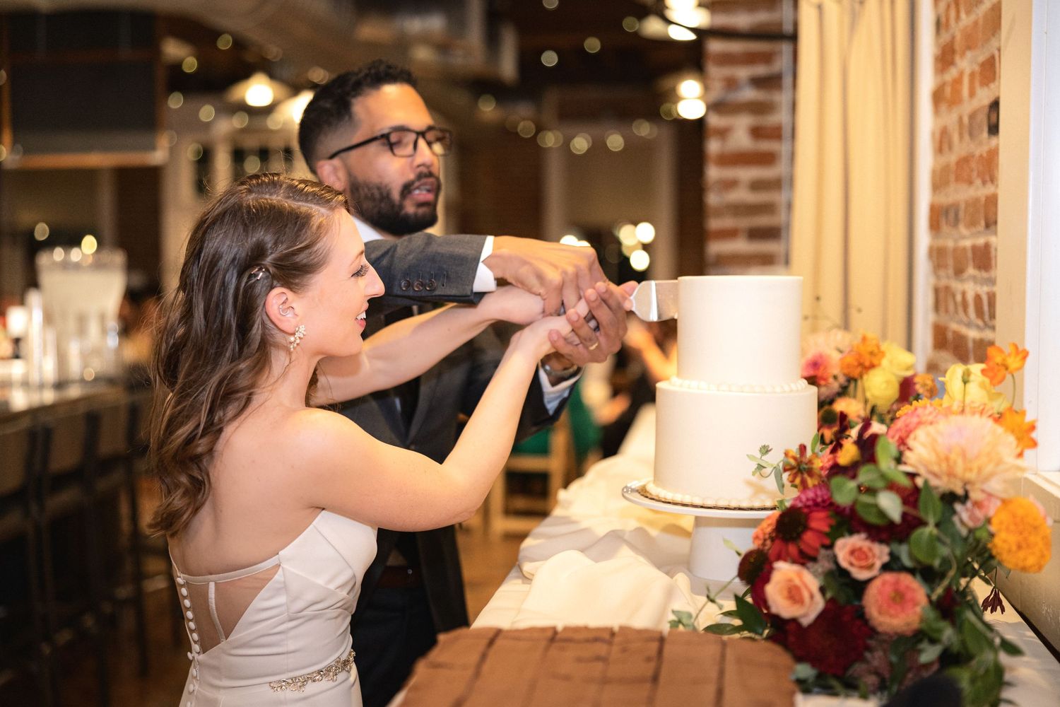 A wedding cake cutting moment at a reception with floral decorations.