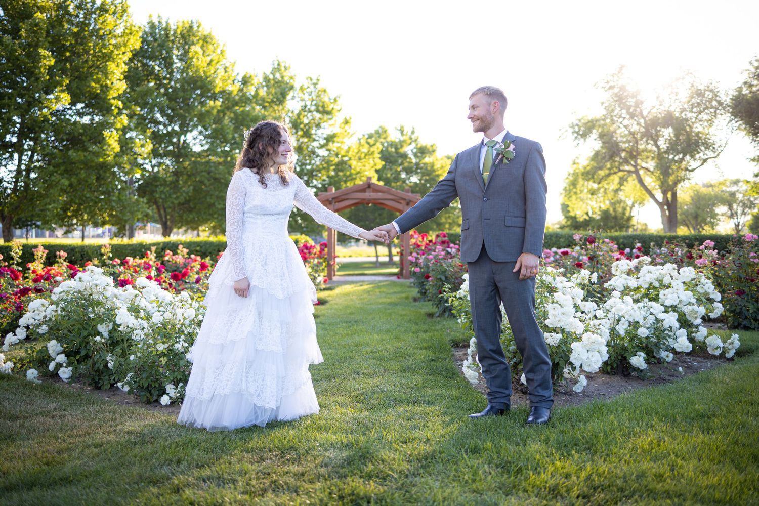 Wedding couple posing in beautiful garden with white and red roses.