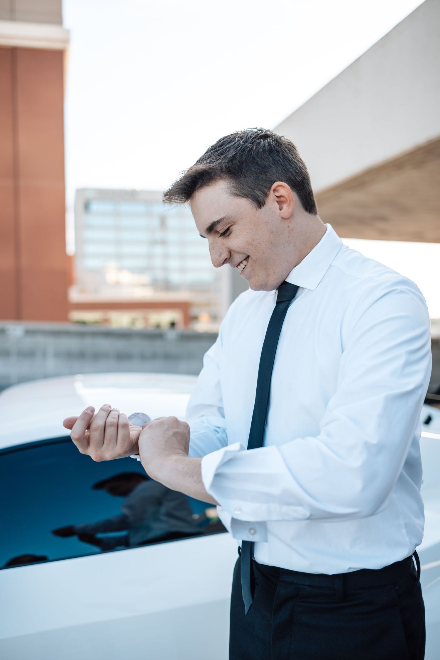 Professional adjusting tie and collar in white dress shirt and black tie against neutral background.