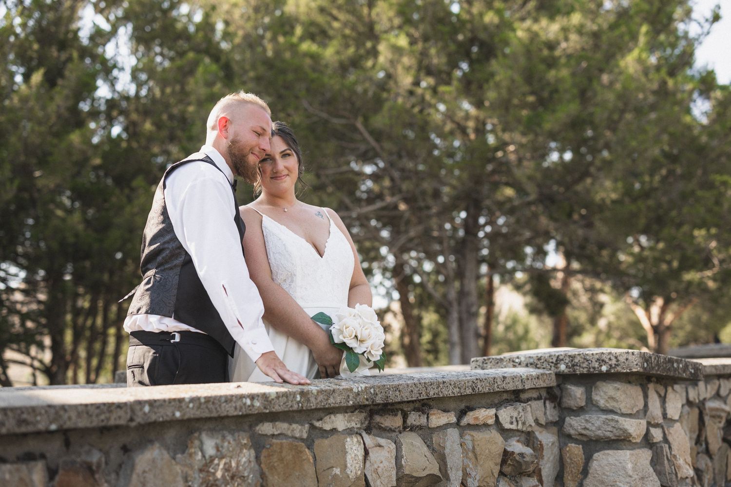 A romantic moment captured on a stone bridge during an outdoor wedding photoshoot.