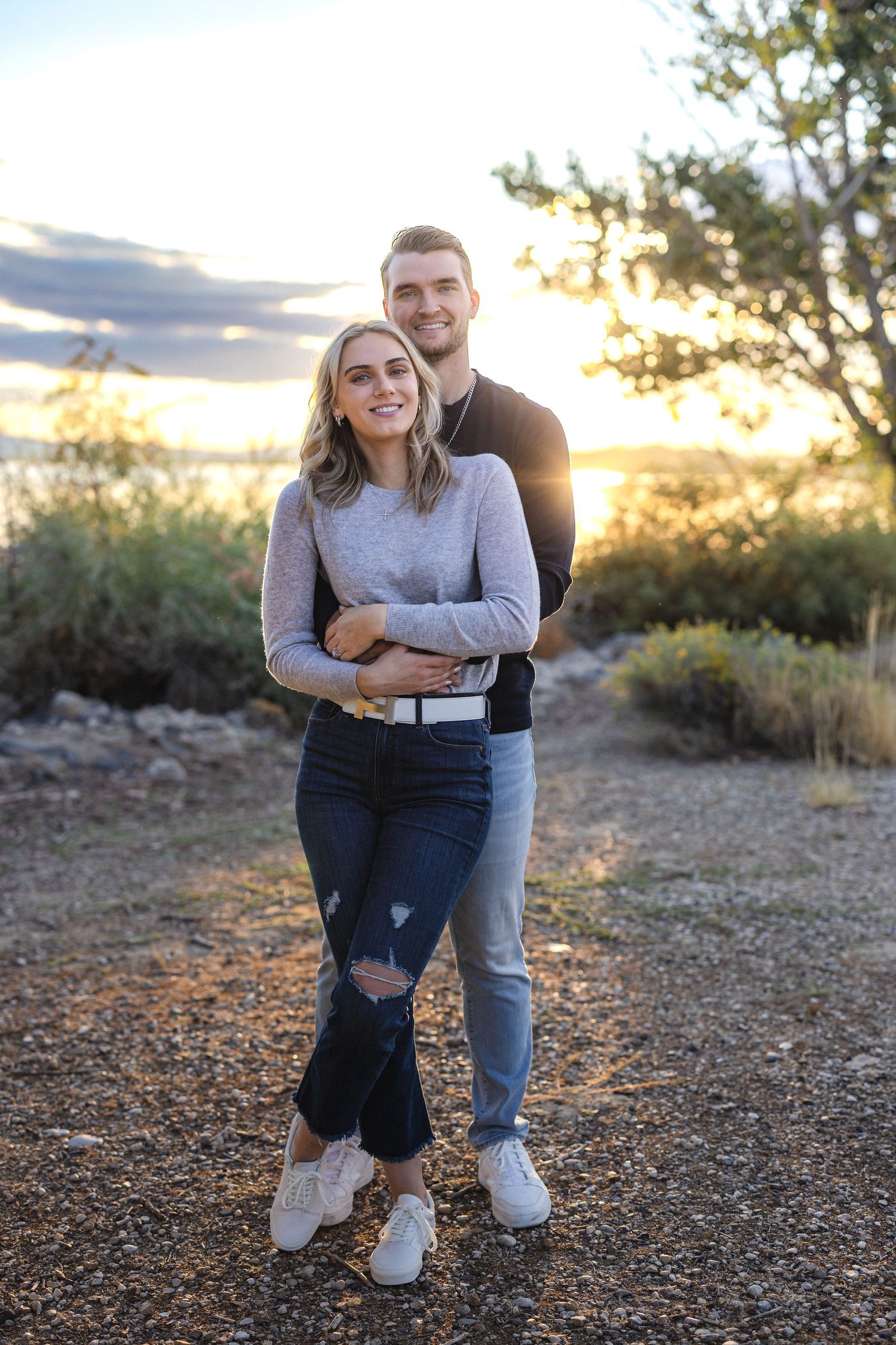 Happy couple posing together against sunset sky in outdoor nature setting.