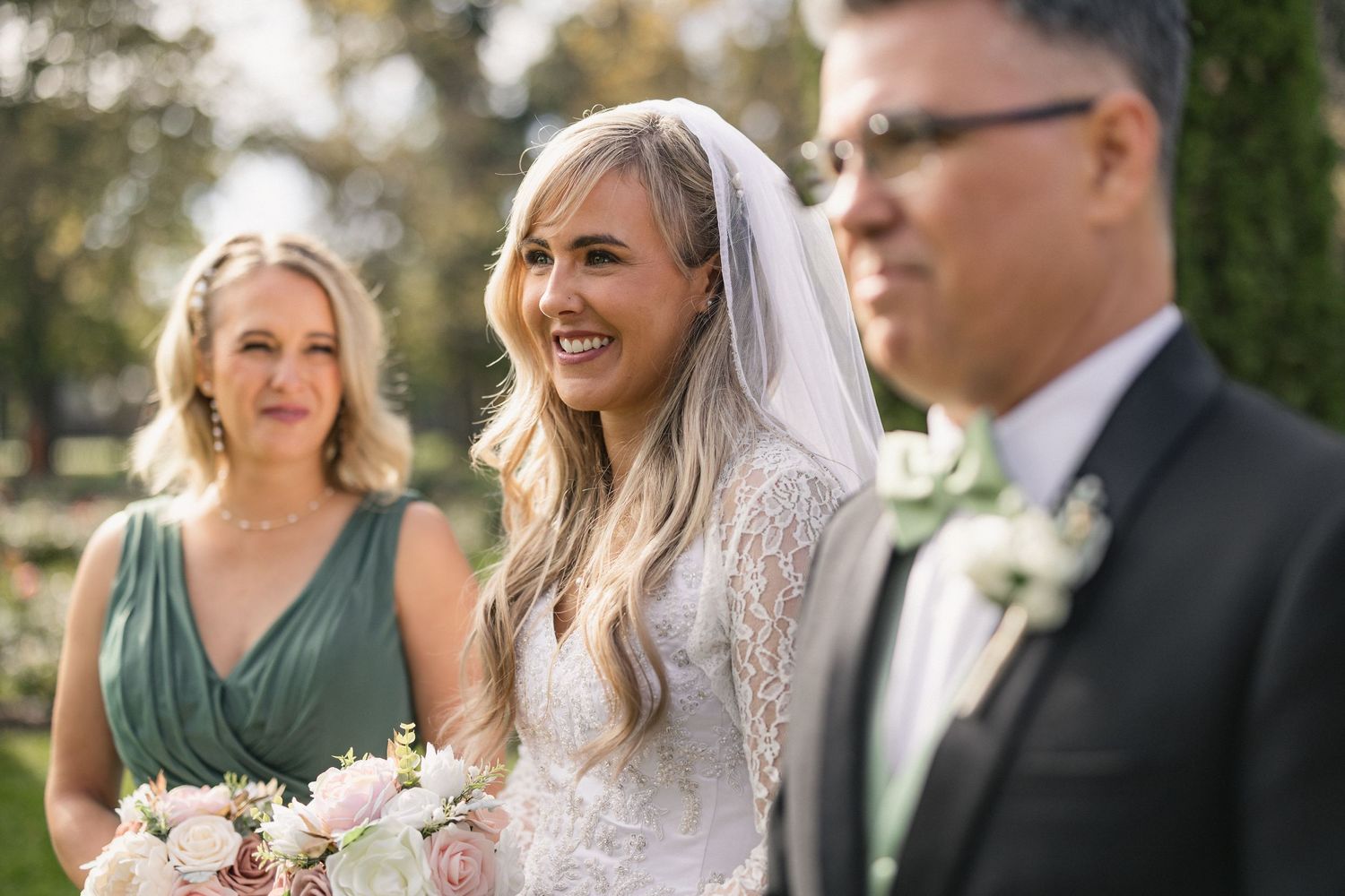 Wedding party members pose together during an outdoor garden ceremony.