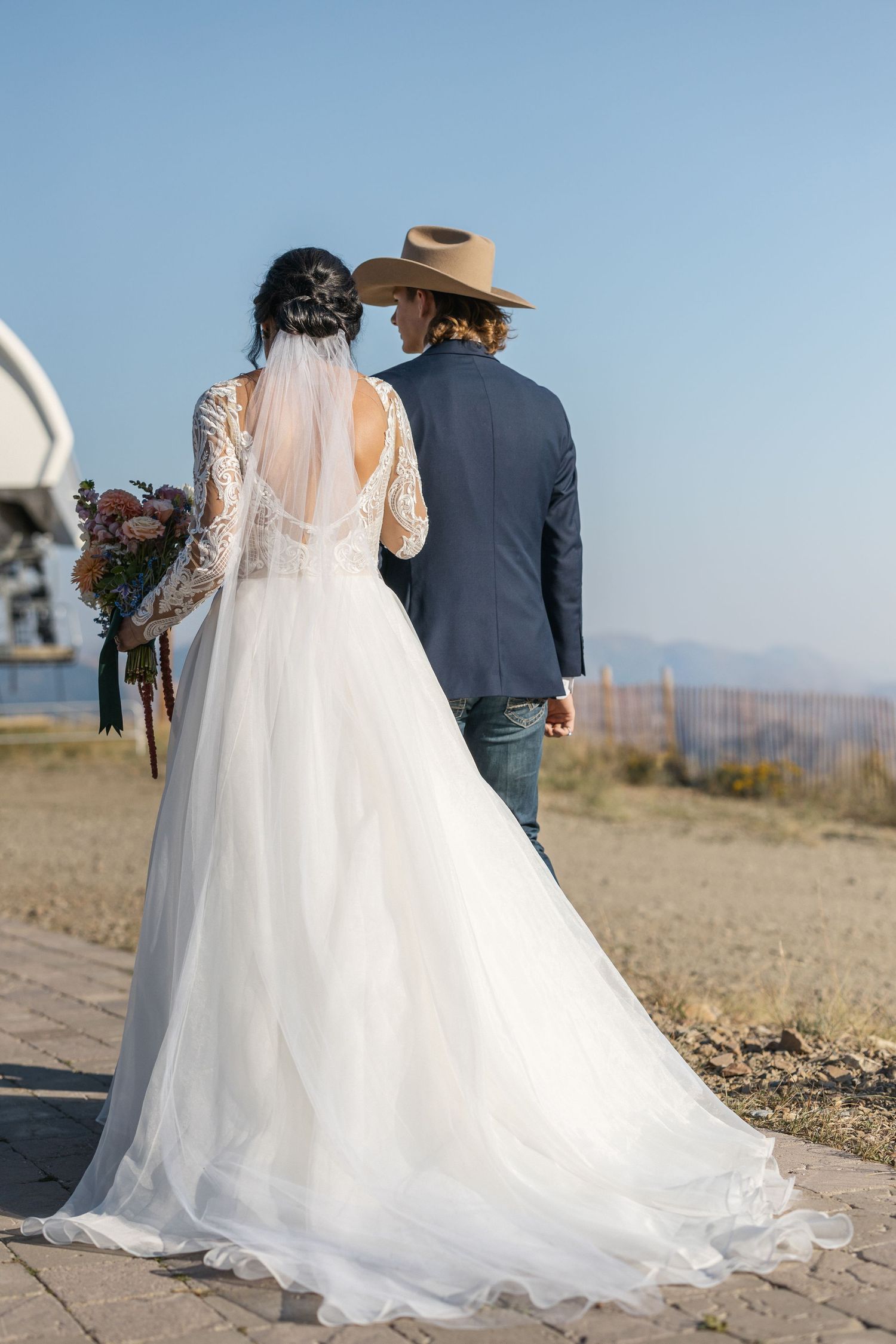 Elegant white wedding dress with flowing train against mountain backdrop.