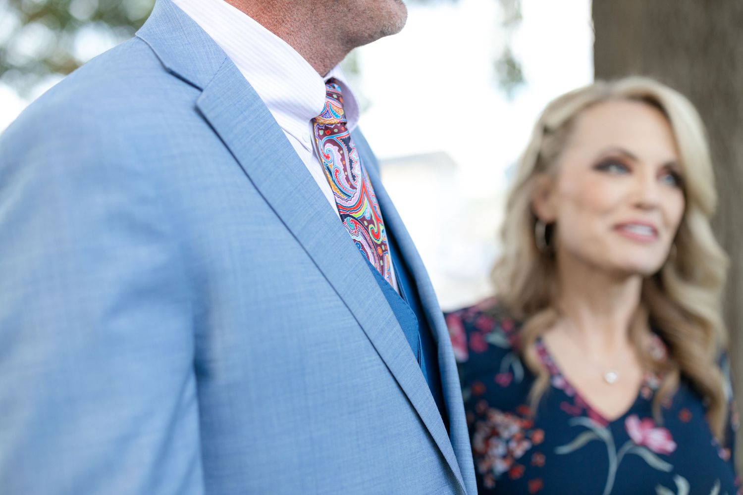 Partial view of couple with light blue suit jacket and floral dress.