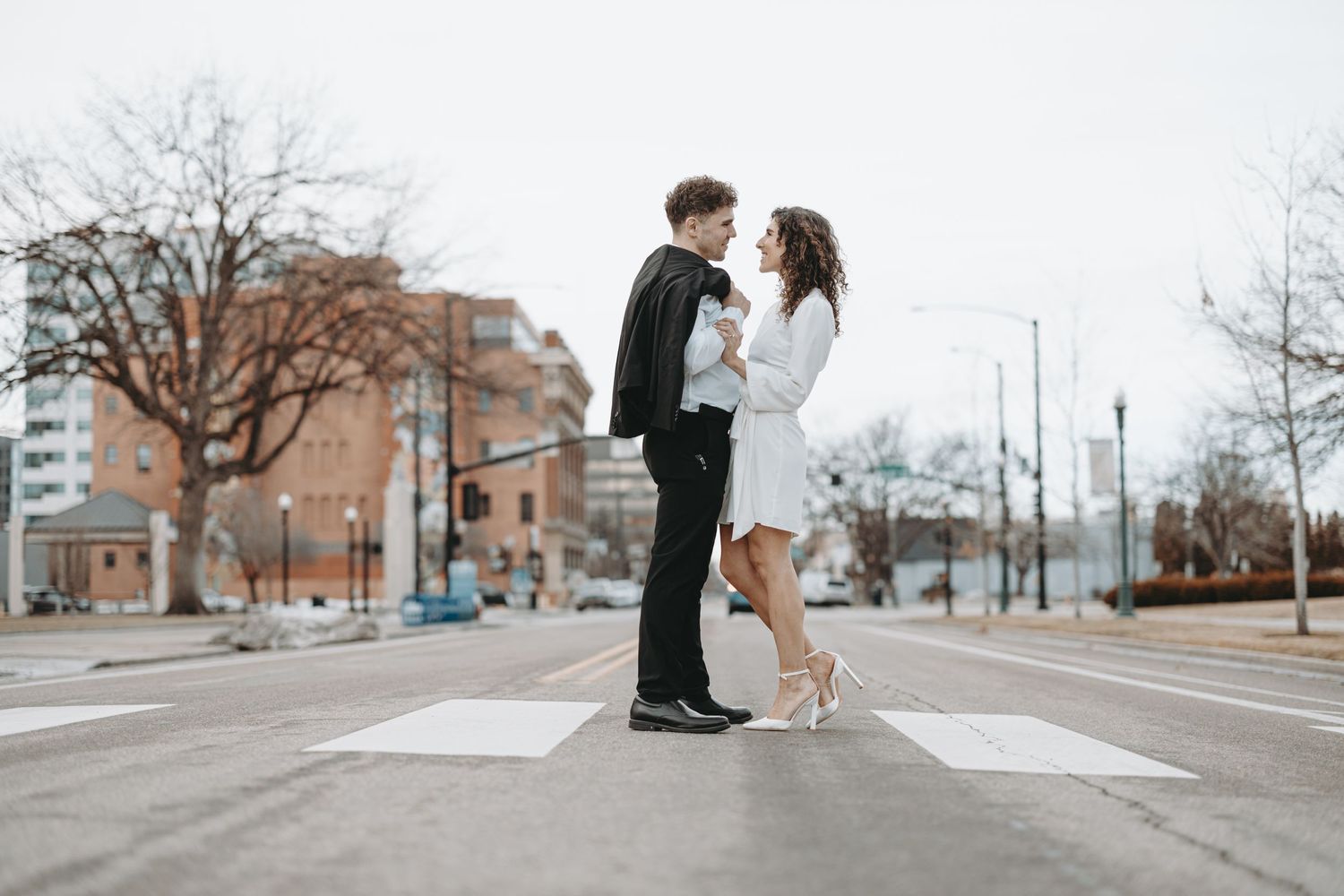 A couple shares an intimate moment while standing on a crosswalk in the city.