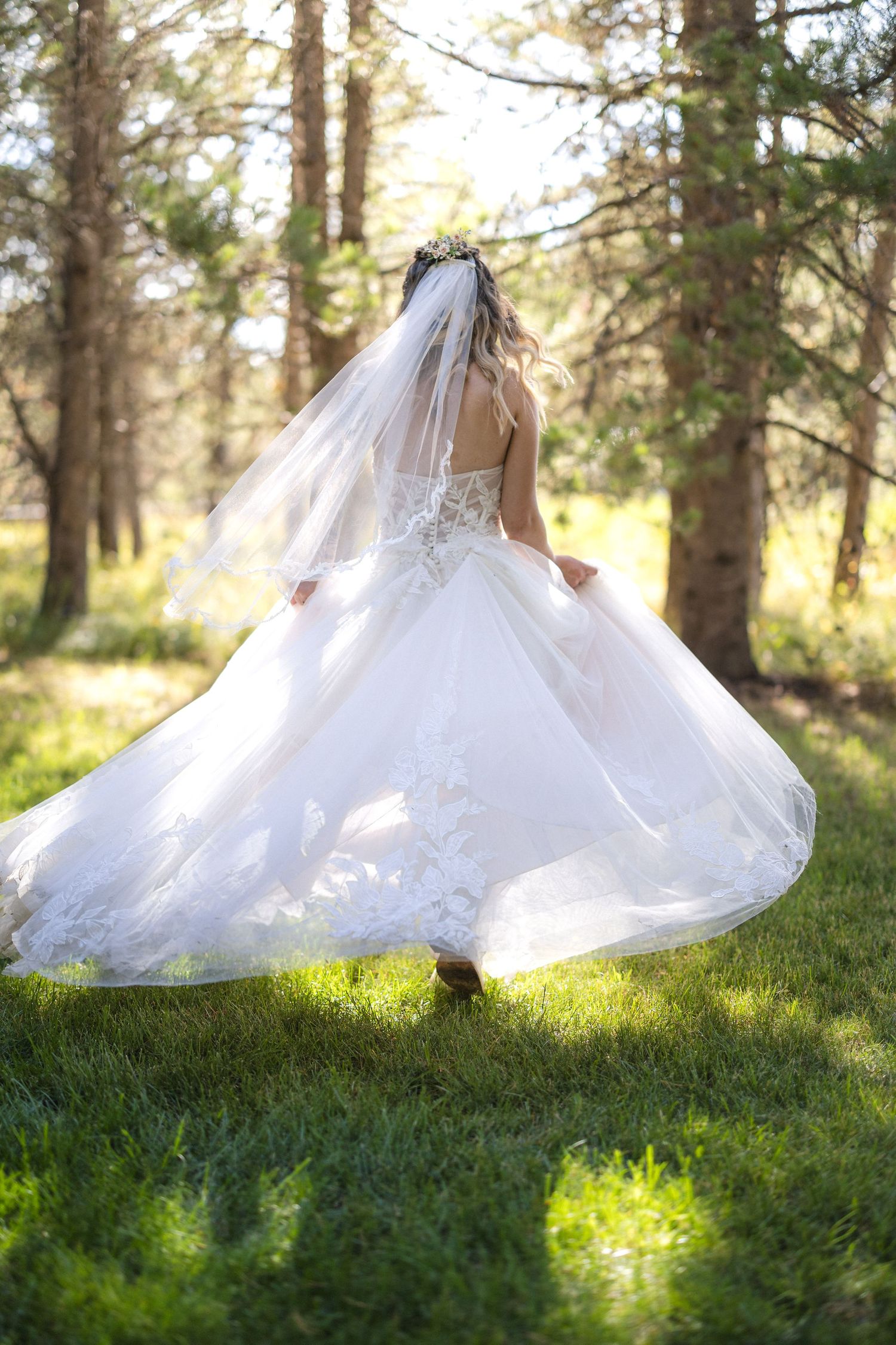 Bride spins in an elegant white wedding gown, creating a dreamy effect in a wooded setting.