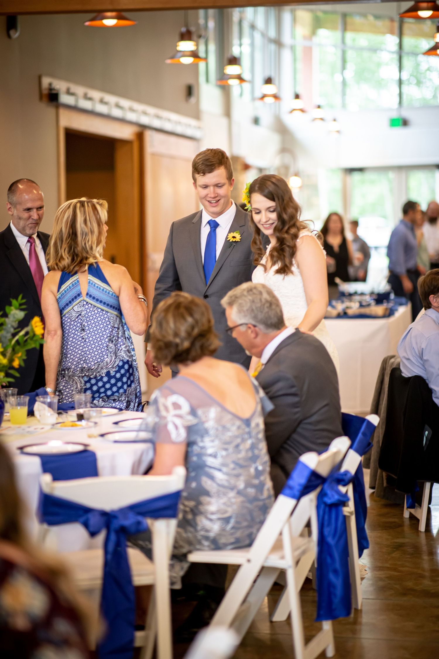 Wedding guests interact during reception at tables decorated with blue accents.