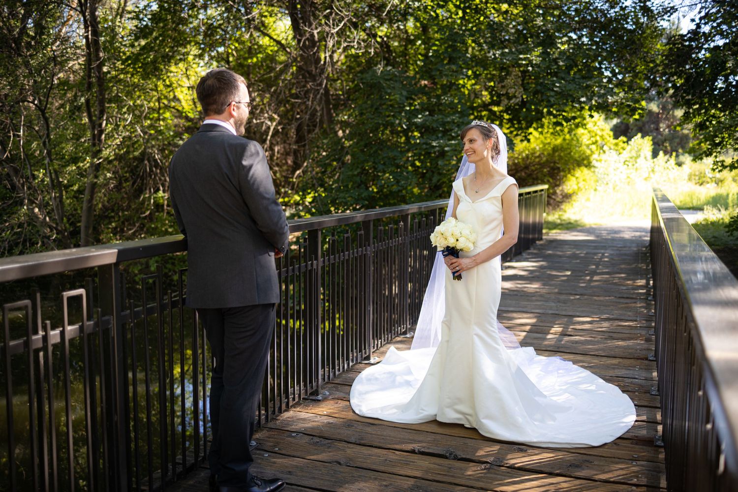 Newlyweds walking along a scenic wooden bridge pathway on their wedding day.