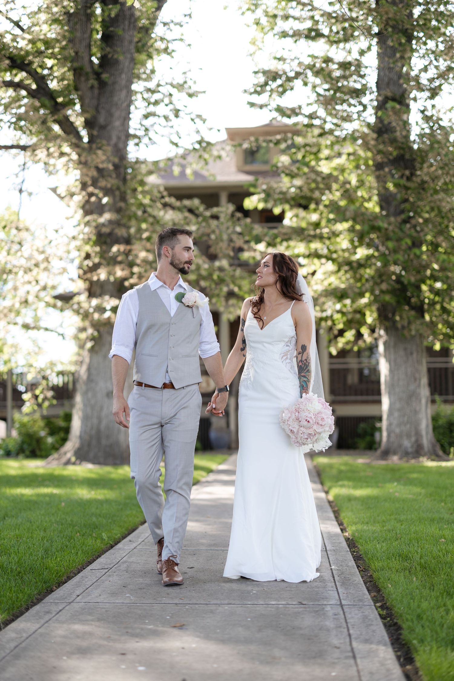 Couple strolling hand in hand on a garden pathway during their wedding day.