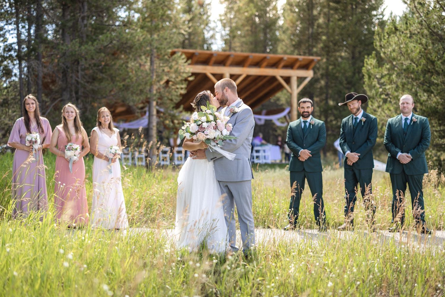Joyful wedding party members pose together in an outdoor mountain setting.