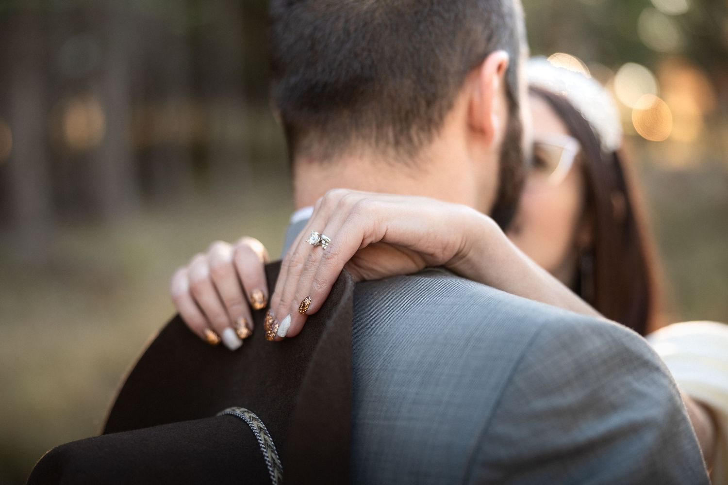 A romantic embrace between a couple outdoors with soft bokeh lighting in the background.
