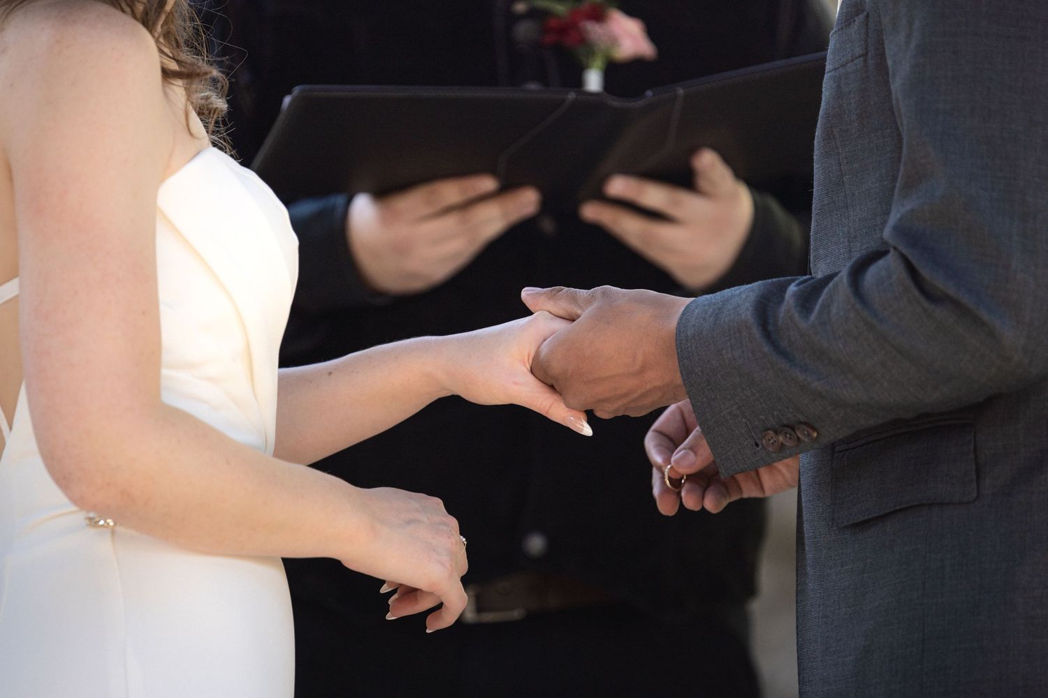 Close-up of hands during wedding ring exchange ceremony.