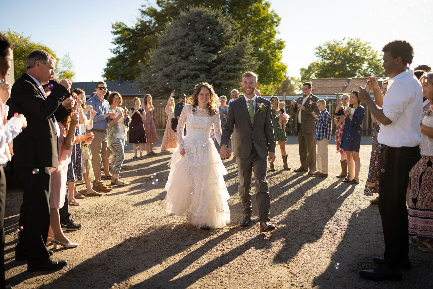 Wedding guests line a path at golden hour to celebrate the newlyweds.