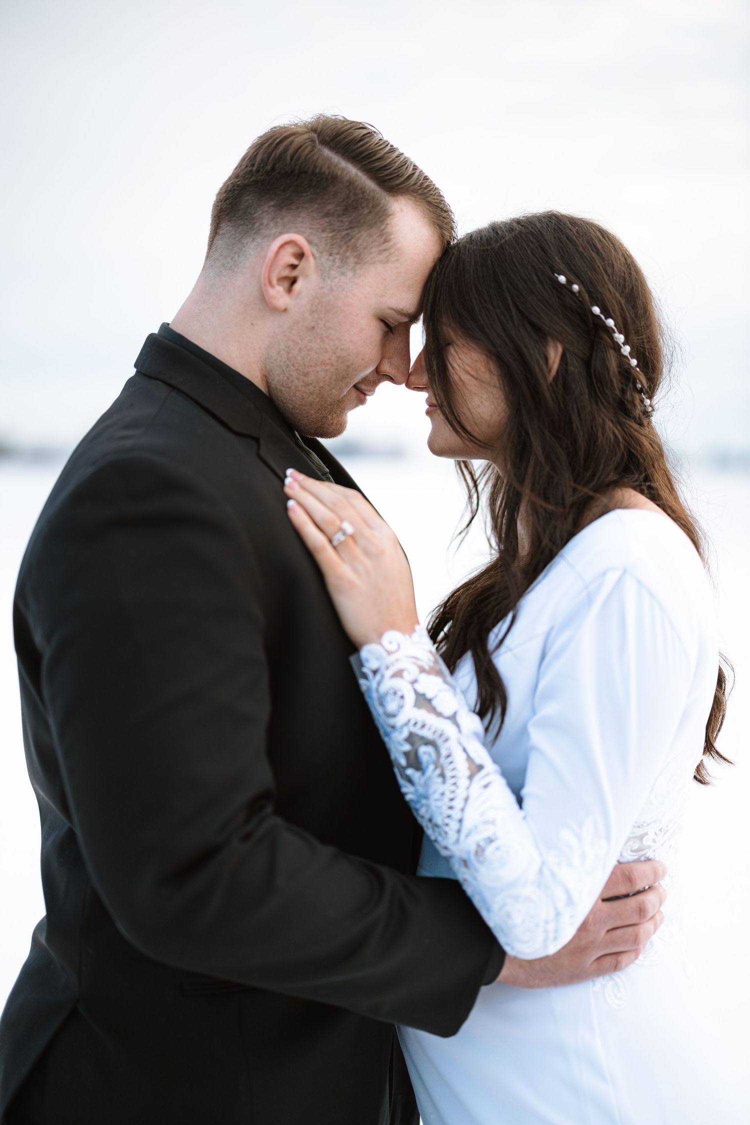 Intimate moment between newlyweds showing lace sleeve detail and engagement ring.