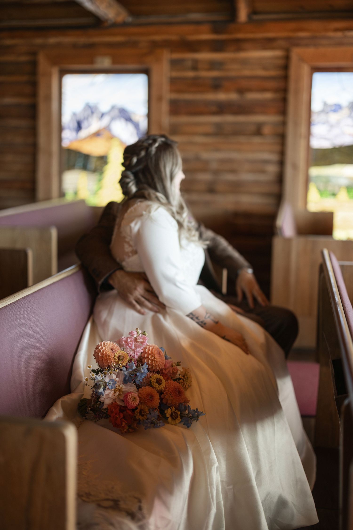 Romantic wedding scene inside rustic wooden cabin with soft natural lighting and floral bouquet details.