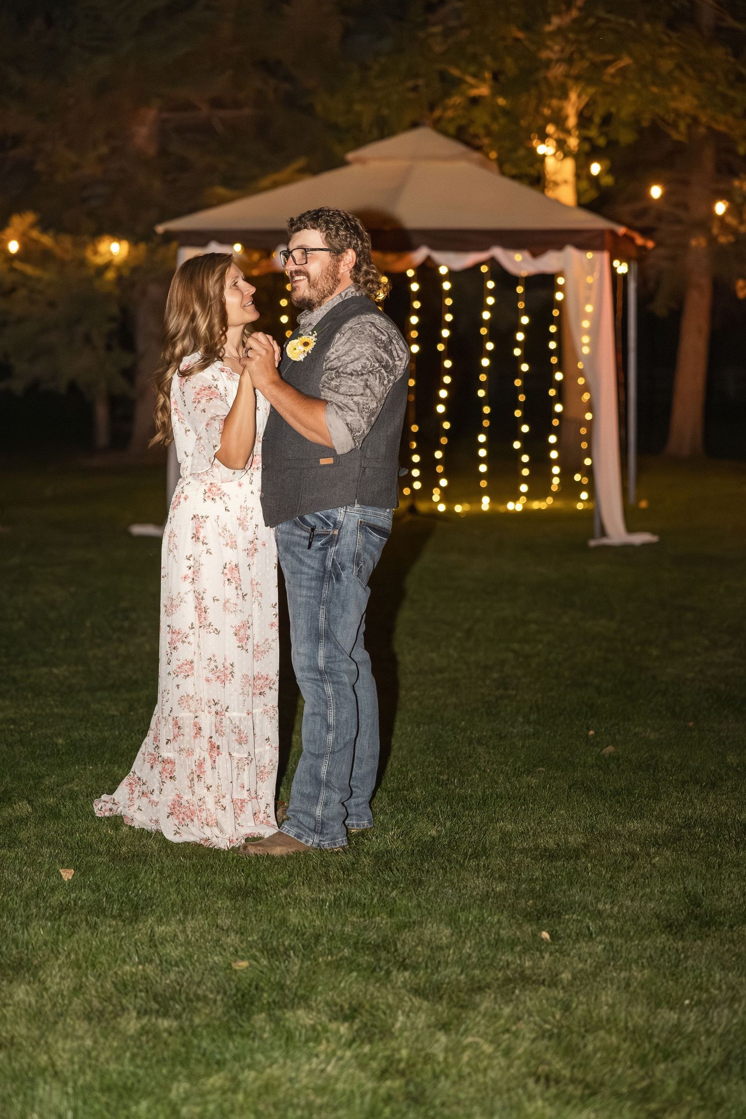A romantic evening dance beneath string lights and a gazebo in a garden setting.