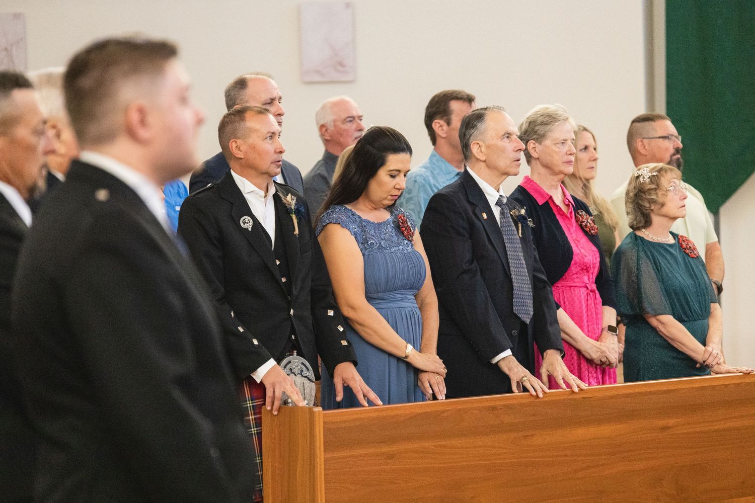 Wedding guests standing in church pews during formal ceremony.