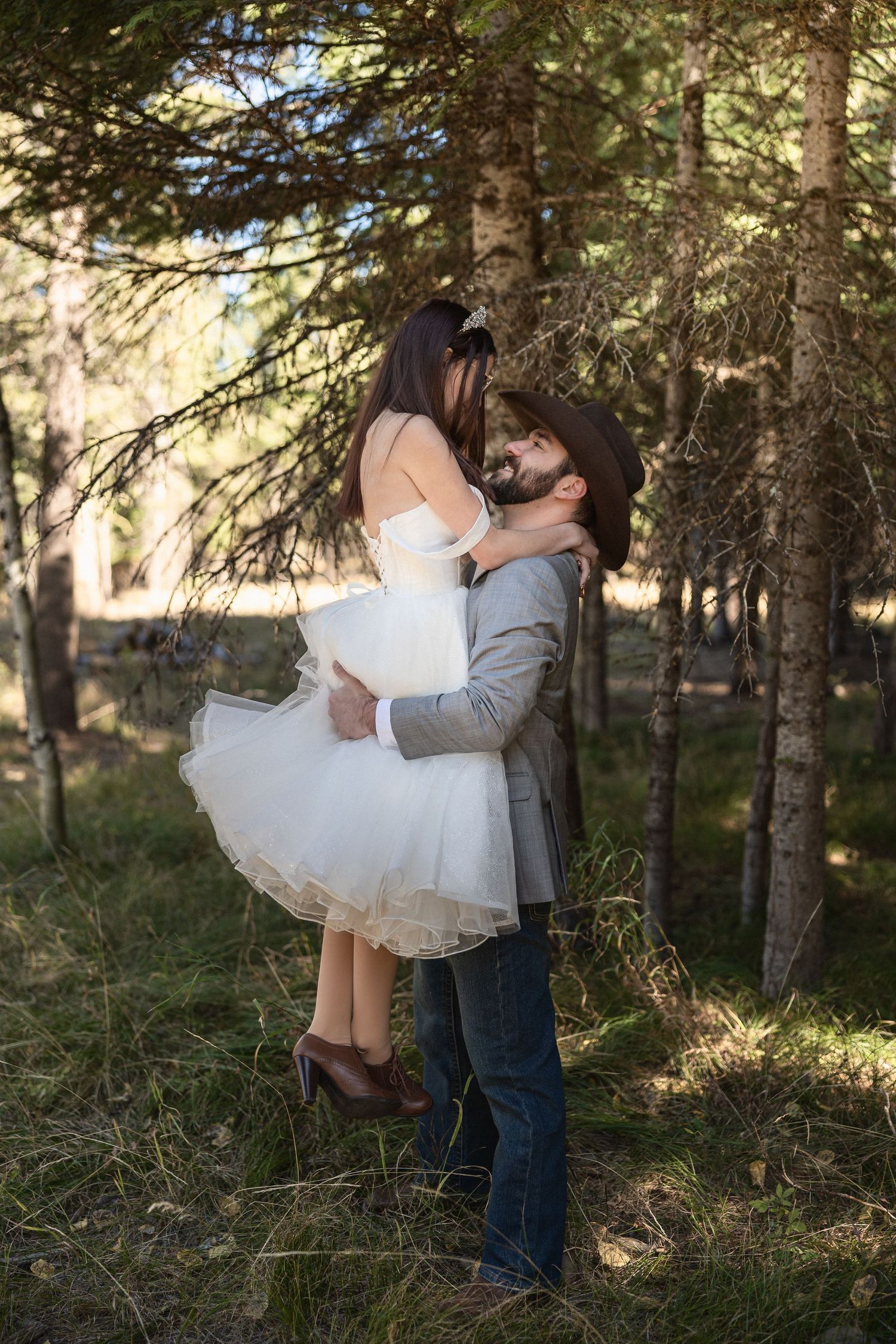 Intimate wedding portraits captured in a sunlit forest with pine trees in the background.