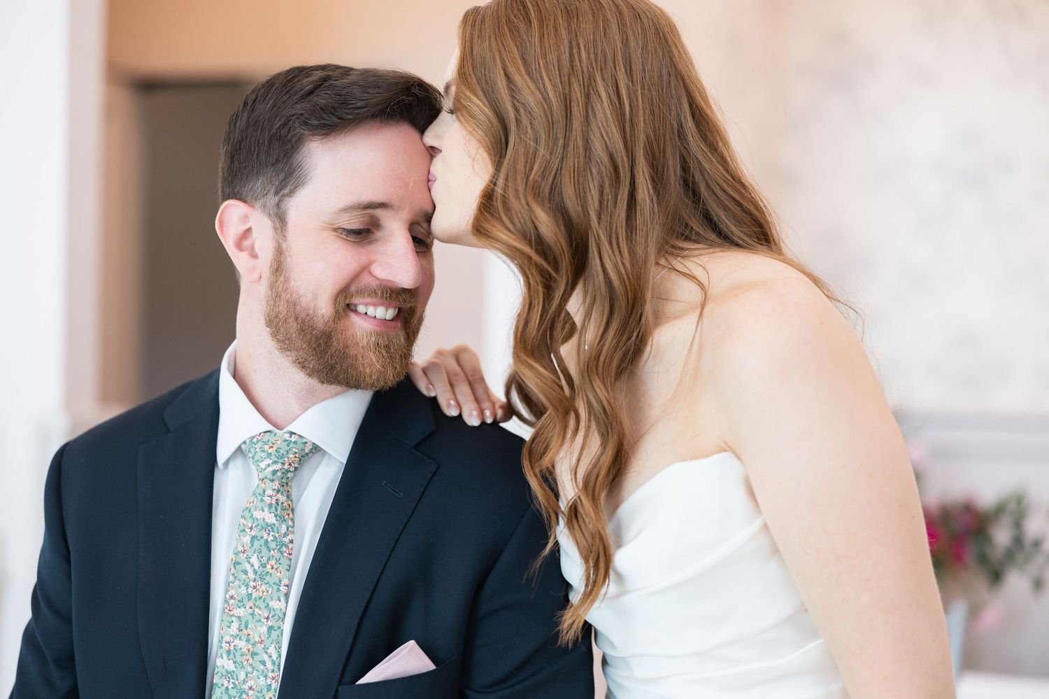Couple shares joyful moments during their first look in an elegant indoor setting.