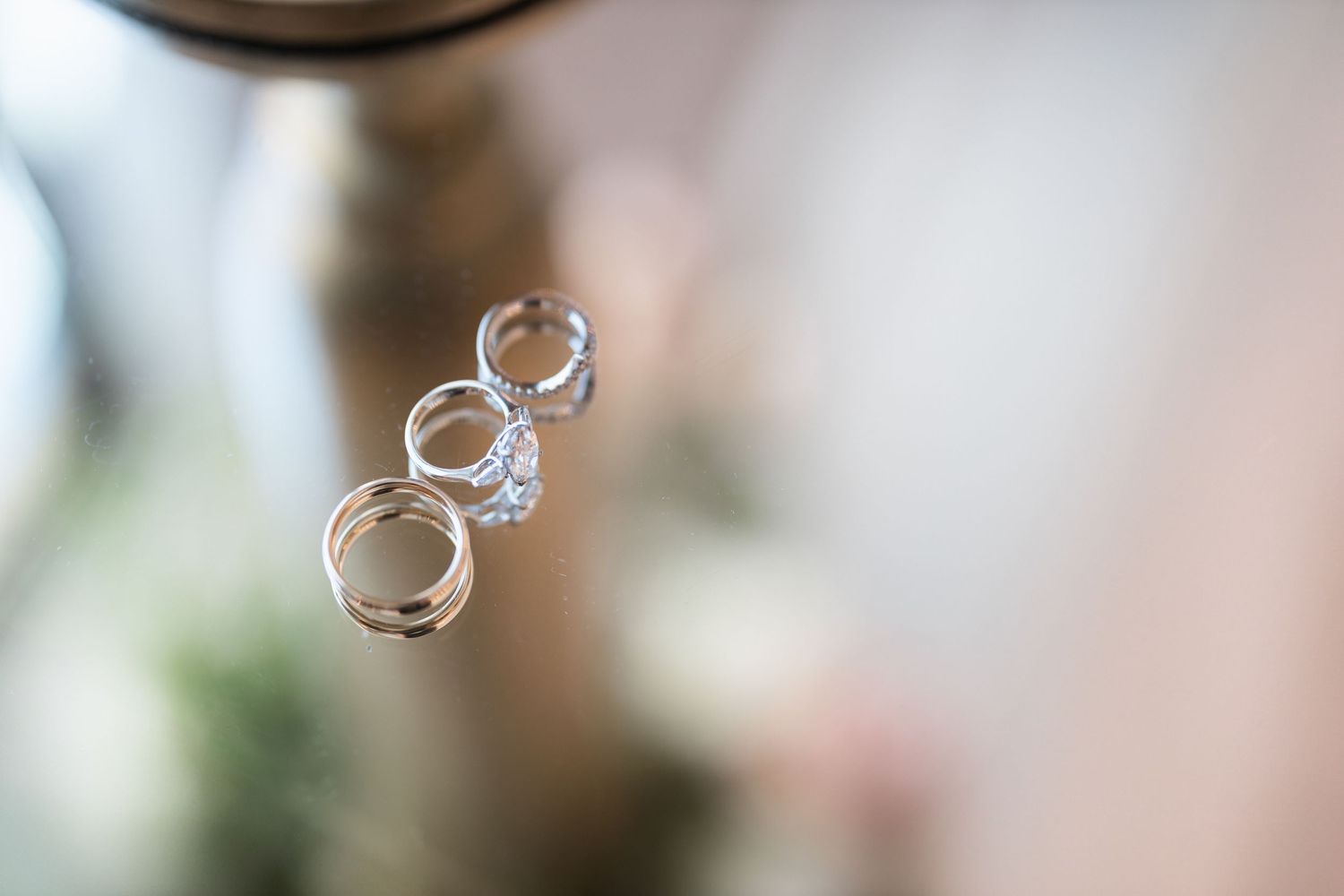 Wedding rings captured in artistic floating photography style against blurred background.