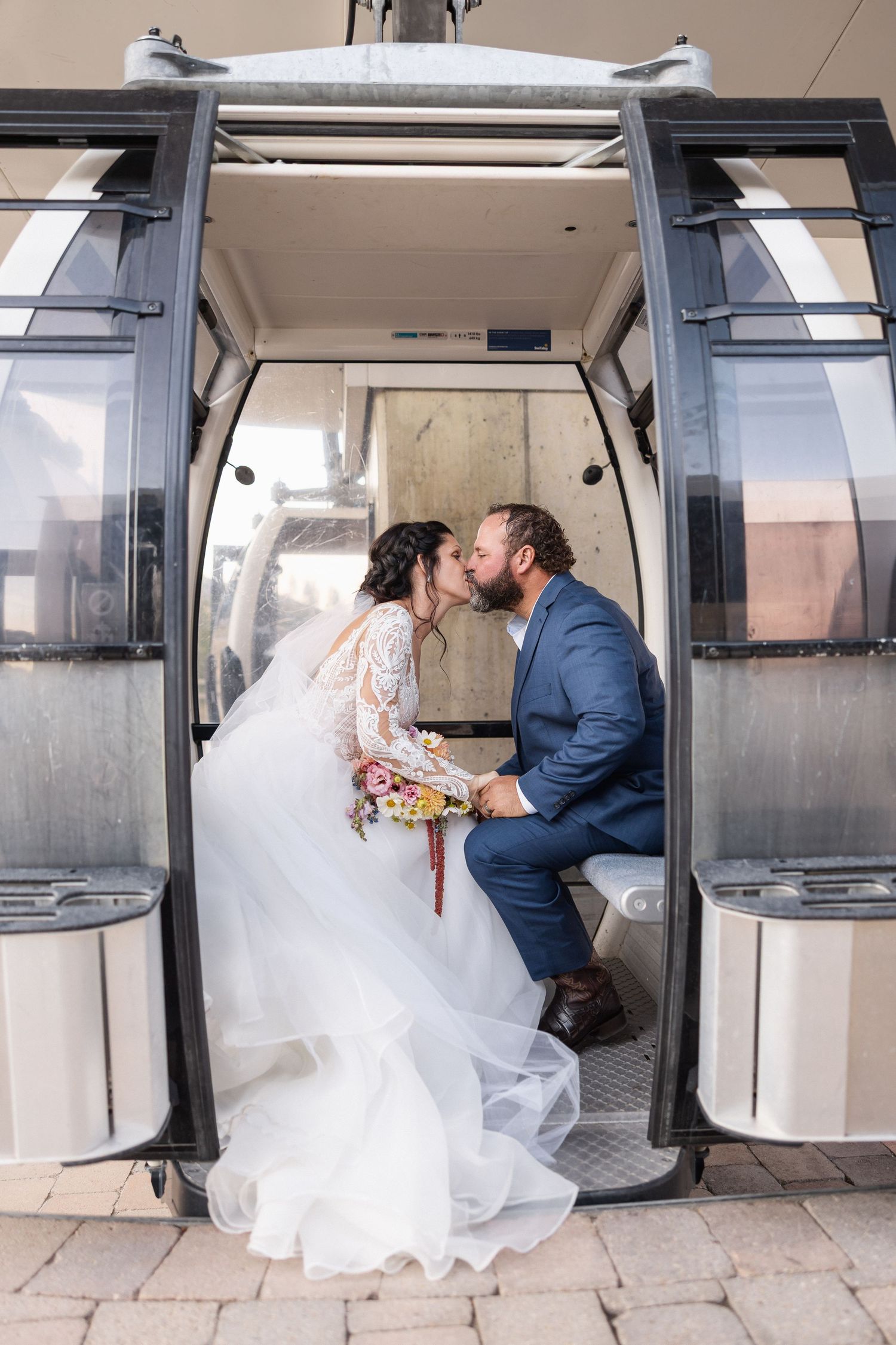 Wedding couple sharing romantic moments inside ski resort gondola cabin.