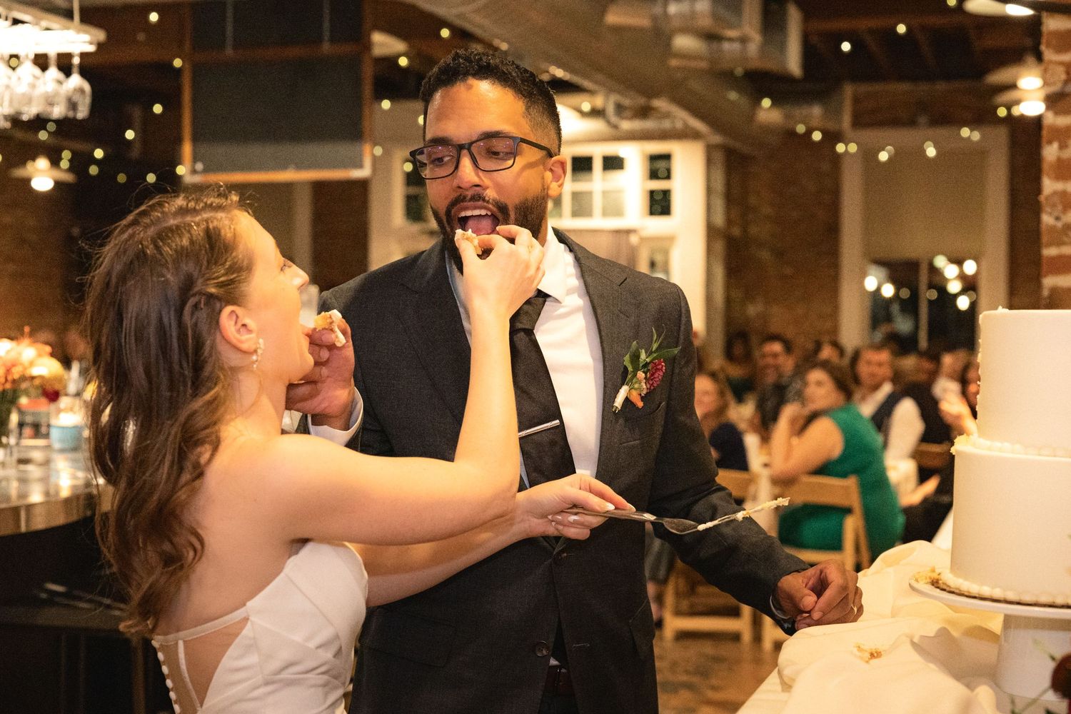 Newlyweds sharing a joyful moment while cutting their wedding cake.