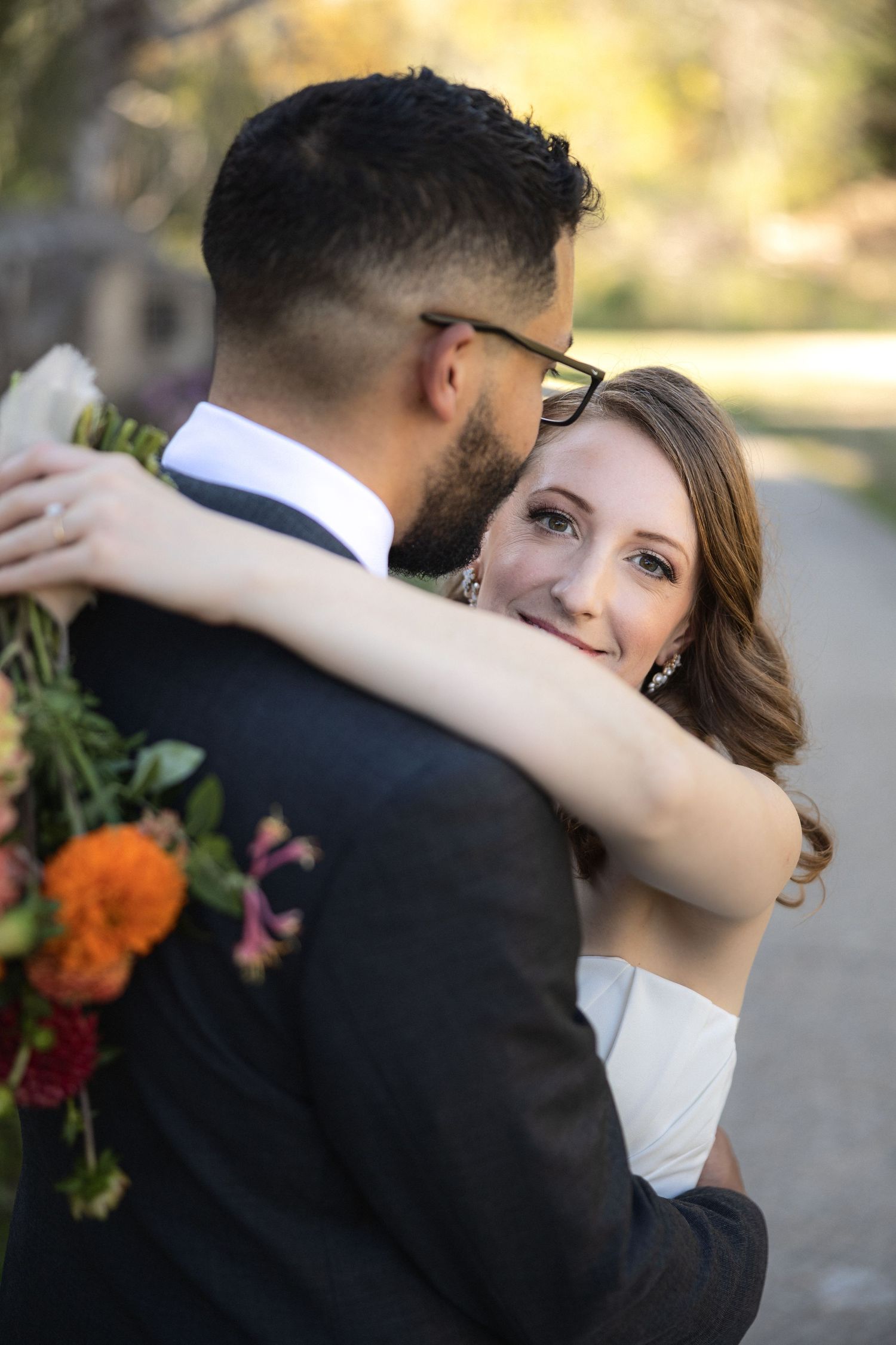 Intimate wedding portrait of couple embracing with vibrant orange florals in garden setting.