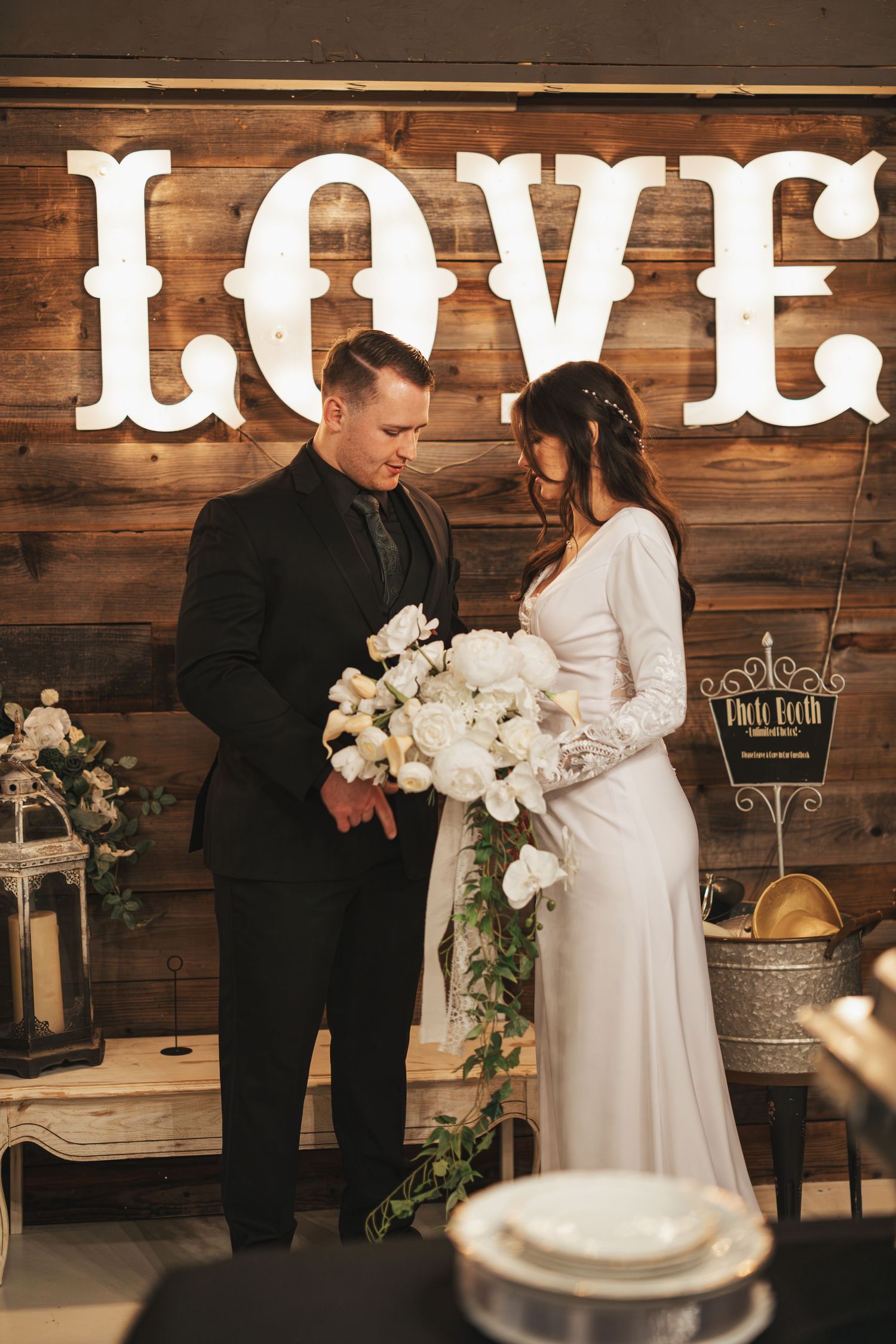 Rustic wedding scene with wooden LOVE sign and white floral decorations.