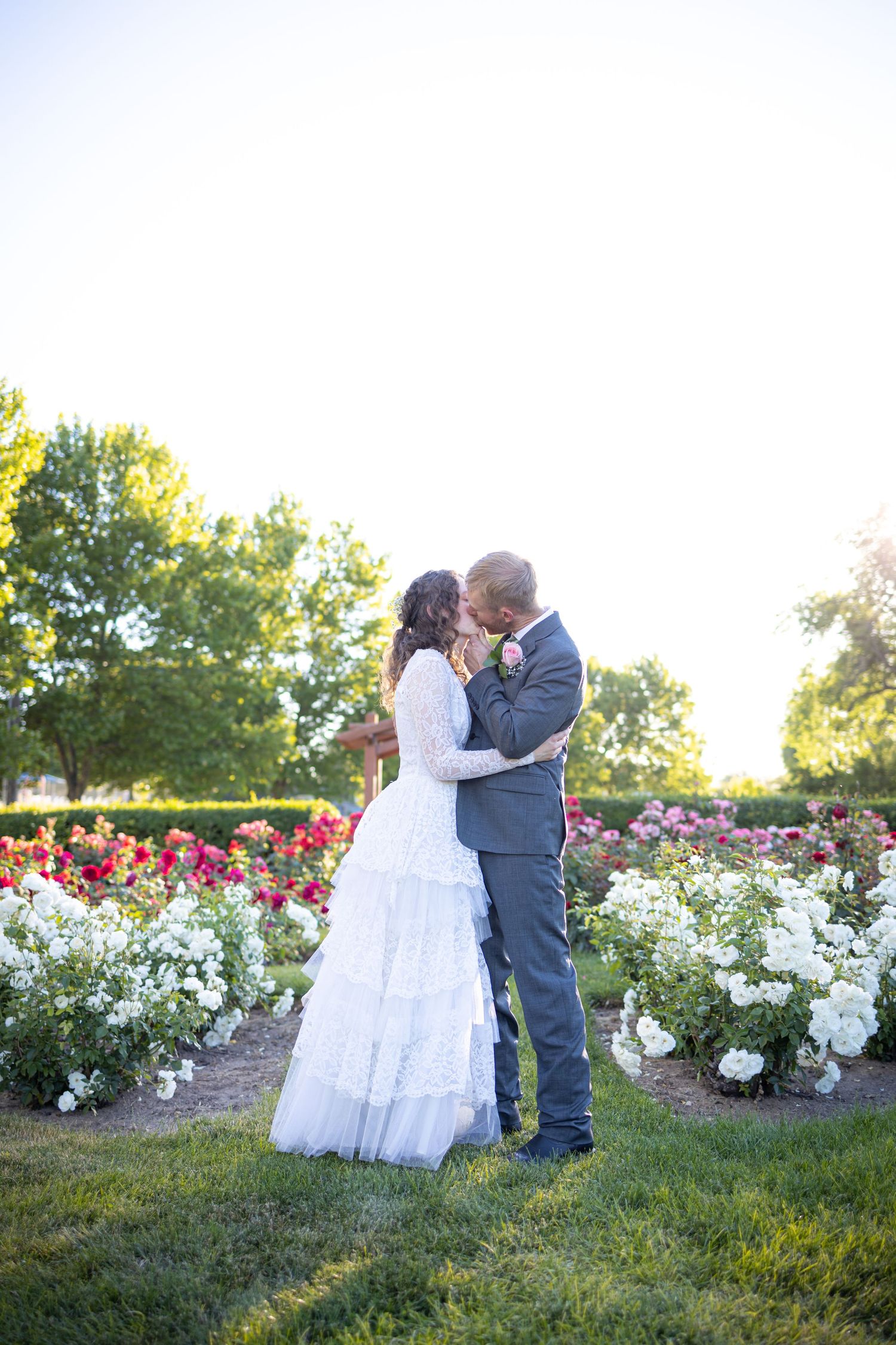 Romantic garden wedding portrait surrounded by white flowers at sunset.